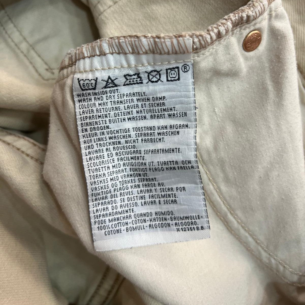 Inquadratura ravvicinata dell'etichetta interna in tessuto stampato con le istruzioni di lavaggio, i codici di produzione e la dicitura Made in Italy.