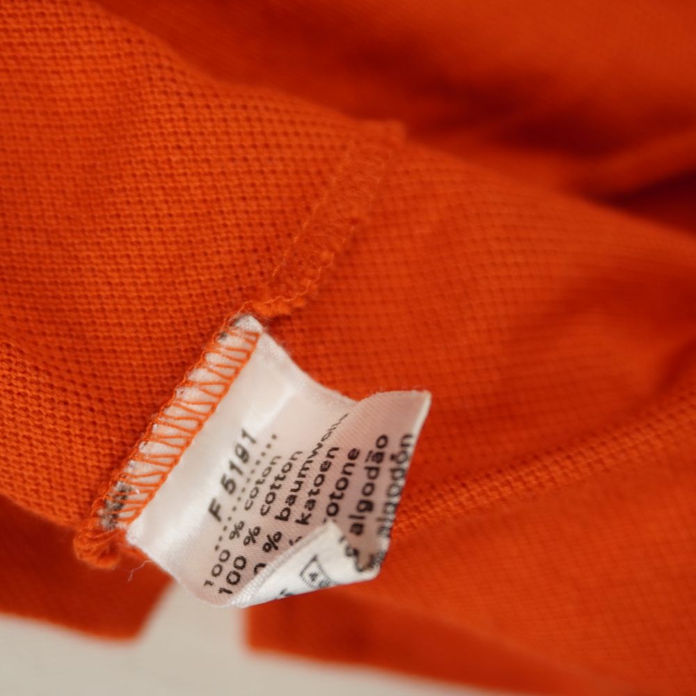 Etichetta interna di composizione 100% cotone e codice modello F 5191 di una polo Lacoste arancione originale