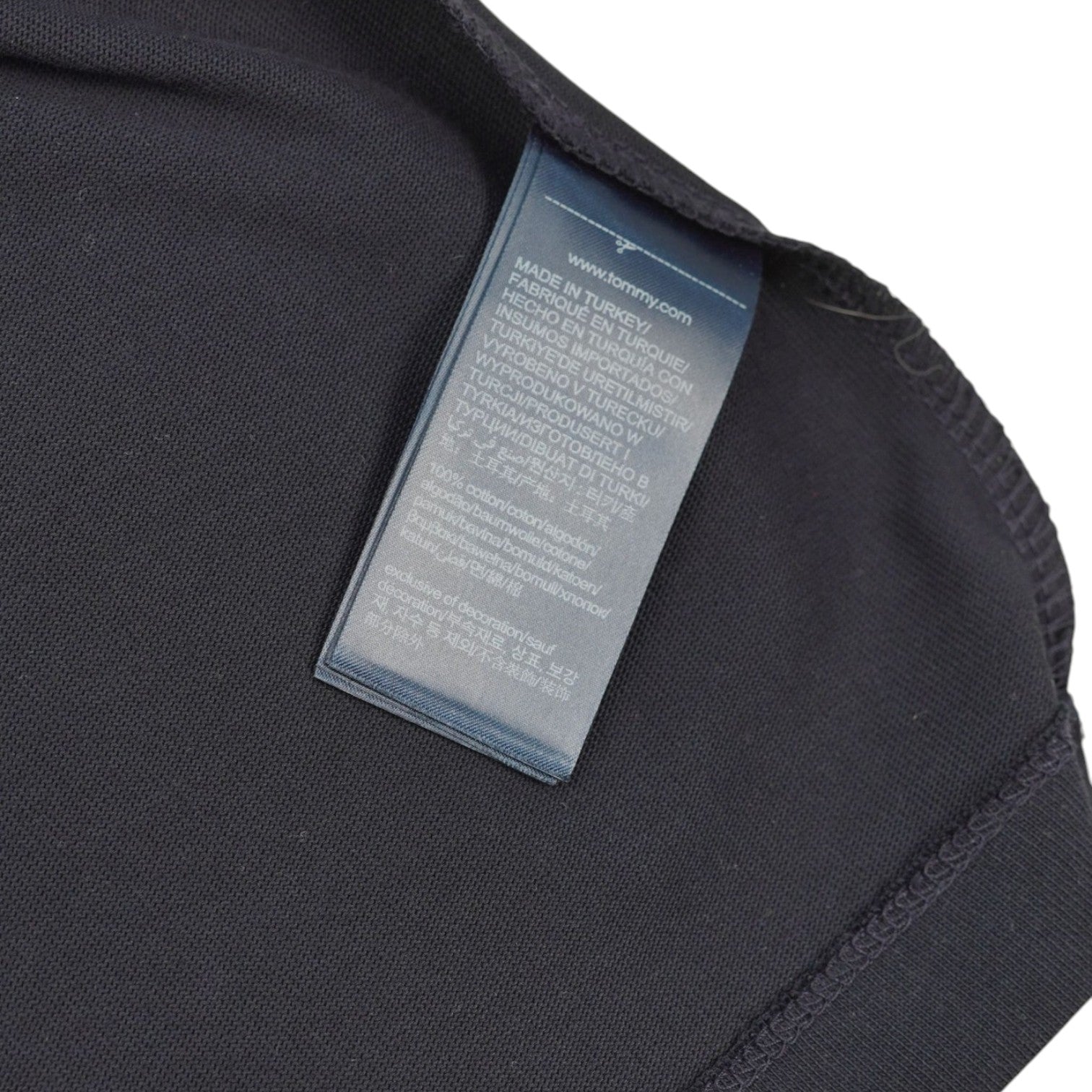 Dettaglio dell'etichetta interna in tessuto con le istruzioni di cura e la composizione 100% cotone premium.
