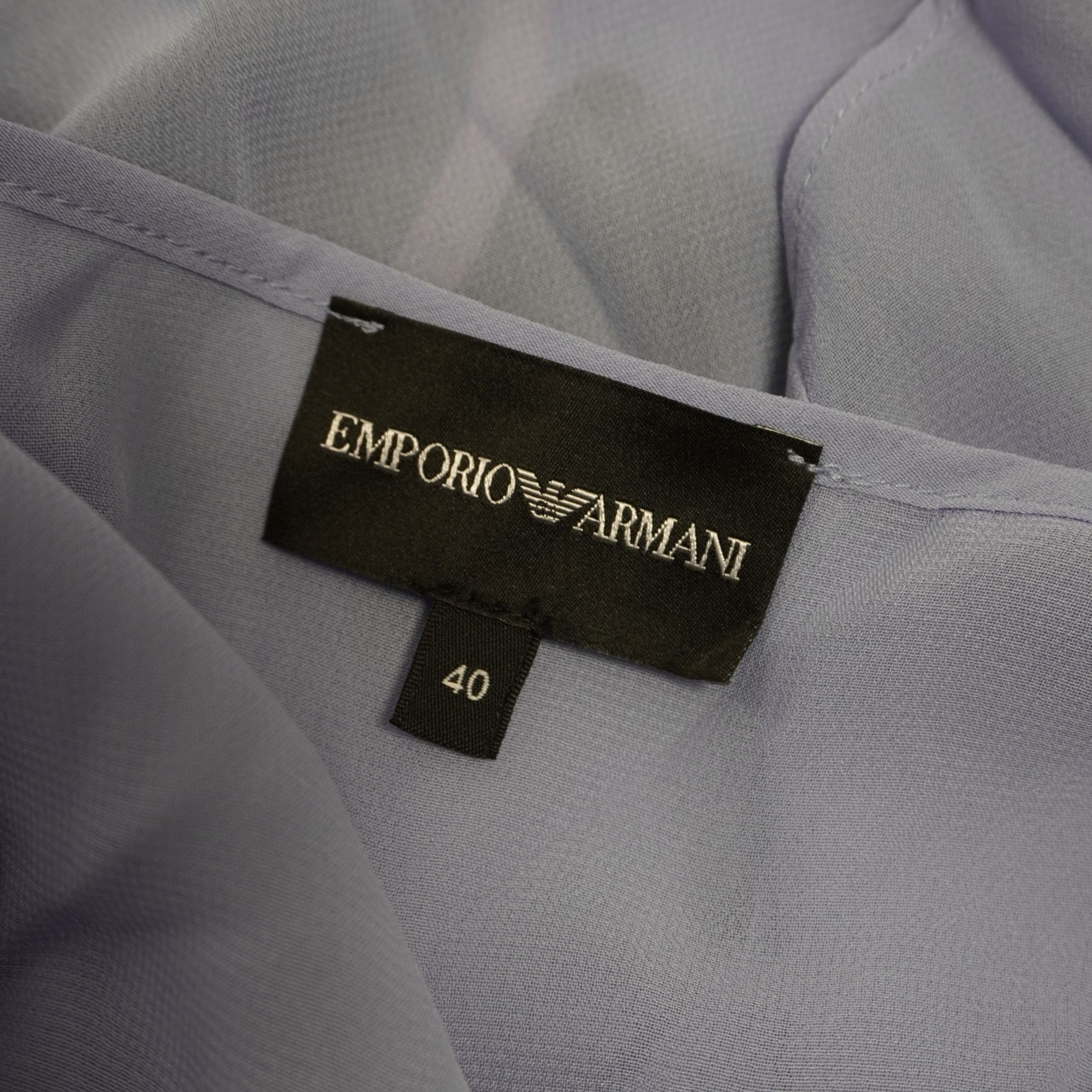 Primo piano dell'etichetta interna nera in tessuto con logo aquila Emporio Armani e indicazione della taglia italiana 40.