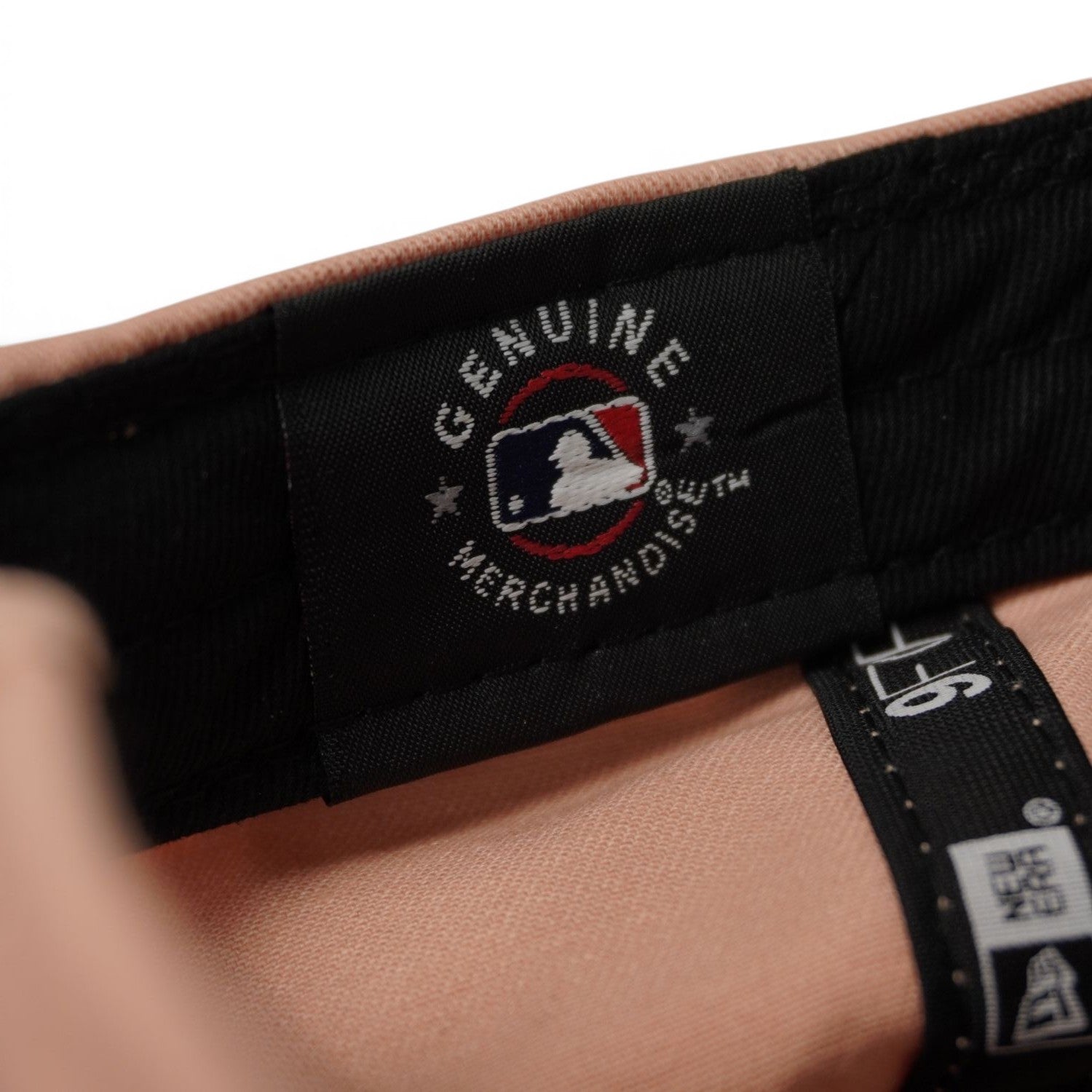 Dettaglio interno dell'etichetta nera Genuine Merchandise con logo del battitore di baseball MLB sulla fascia tergisudore.