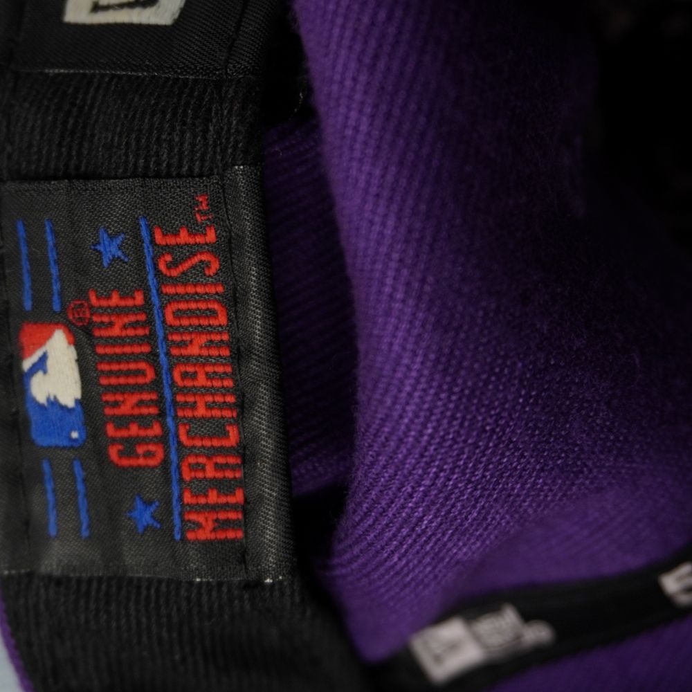 Primo piano dell'etichetta interna nera Genuine Merchandise con logo ricamato MLB Major League Baseball sulla fascia tergisudore.