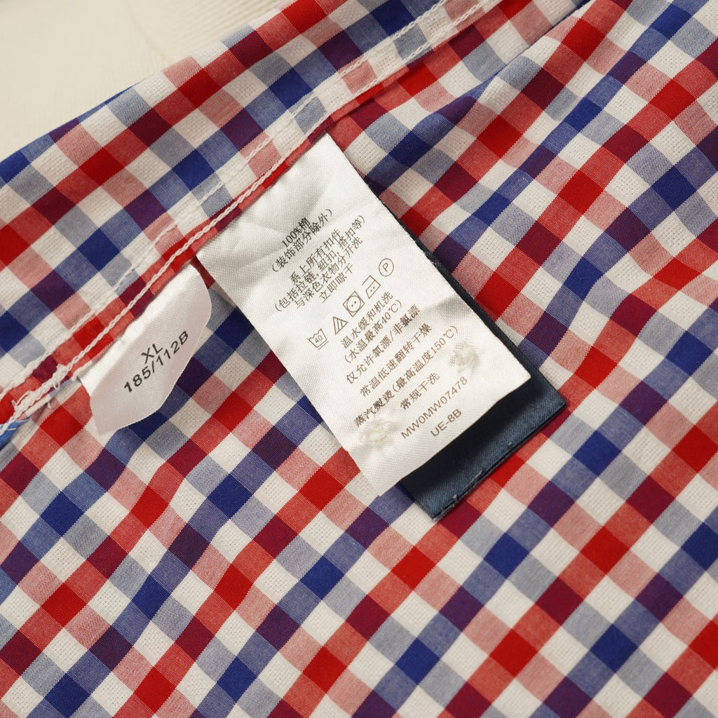 Primo piano delle etichette interne in tessuto bianco con istruzioni di lavaggio e codice di autenticità della camicia.