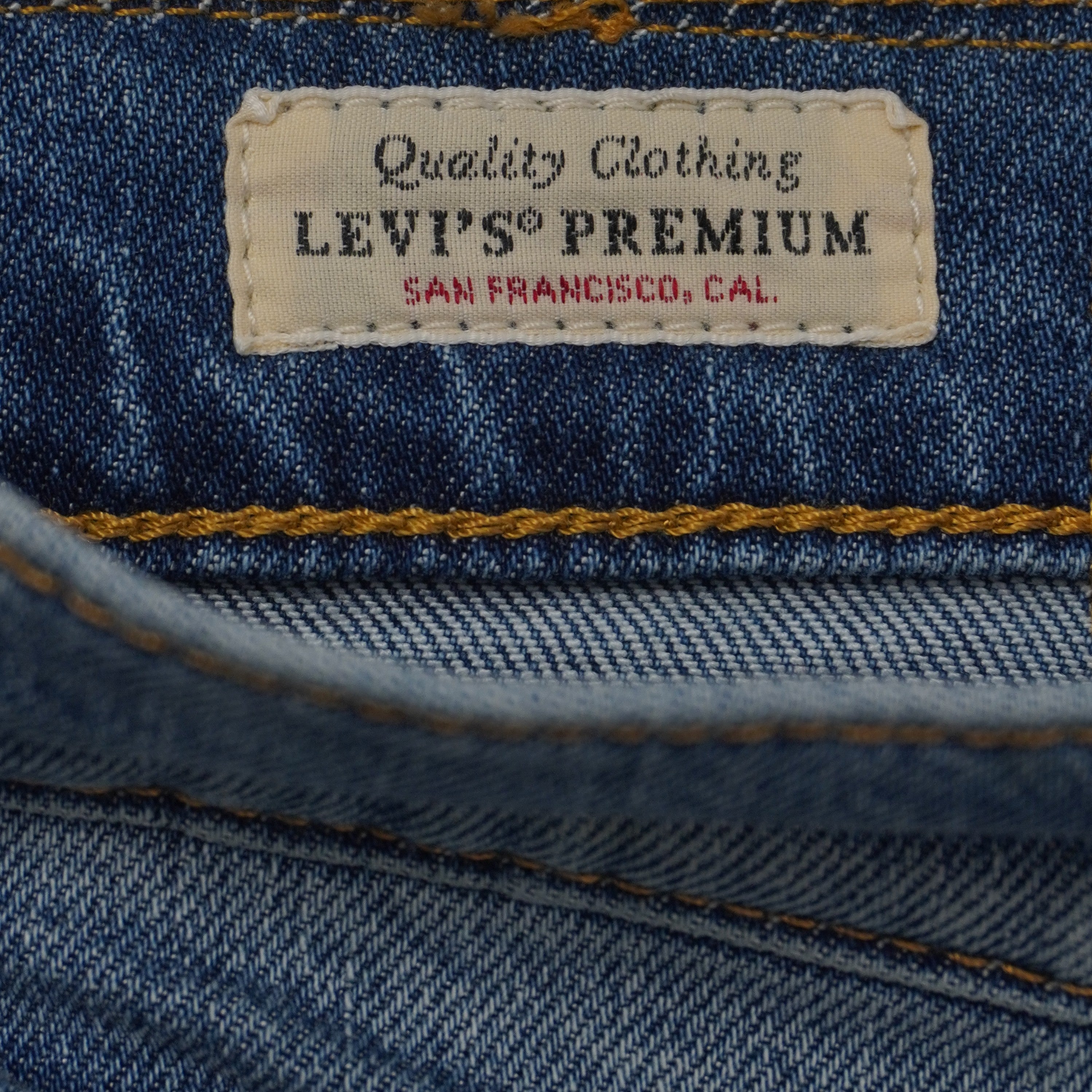 Primo piano dell'etichetta rettangolare in tessuto cucita all'interno con la scritta dorata Levi's Premium Quality Clothing.