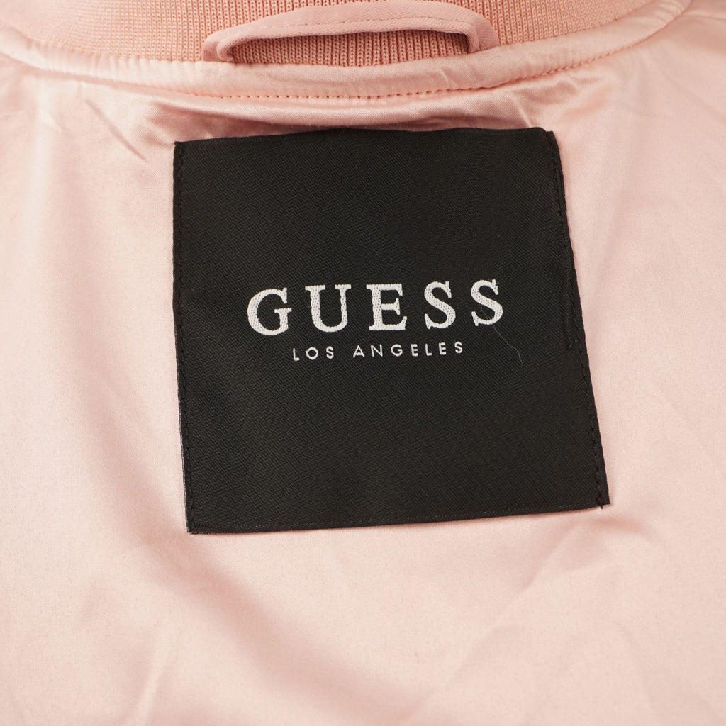 Primo piano dell'etichetta interna quadrata di colore nero con la scritta bianca Guess Los Angeles cucita sotto il colletto.