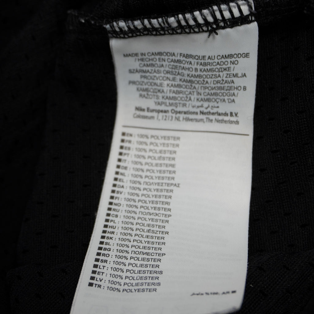 Etichetta interna di produzione Nike con indicazione del materiale 100% poliestere e istruzioni per la cura del capo.