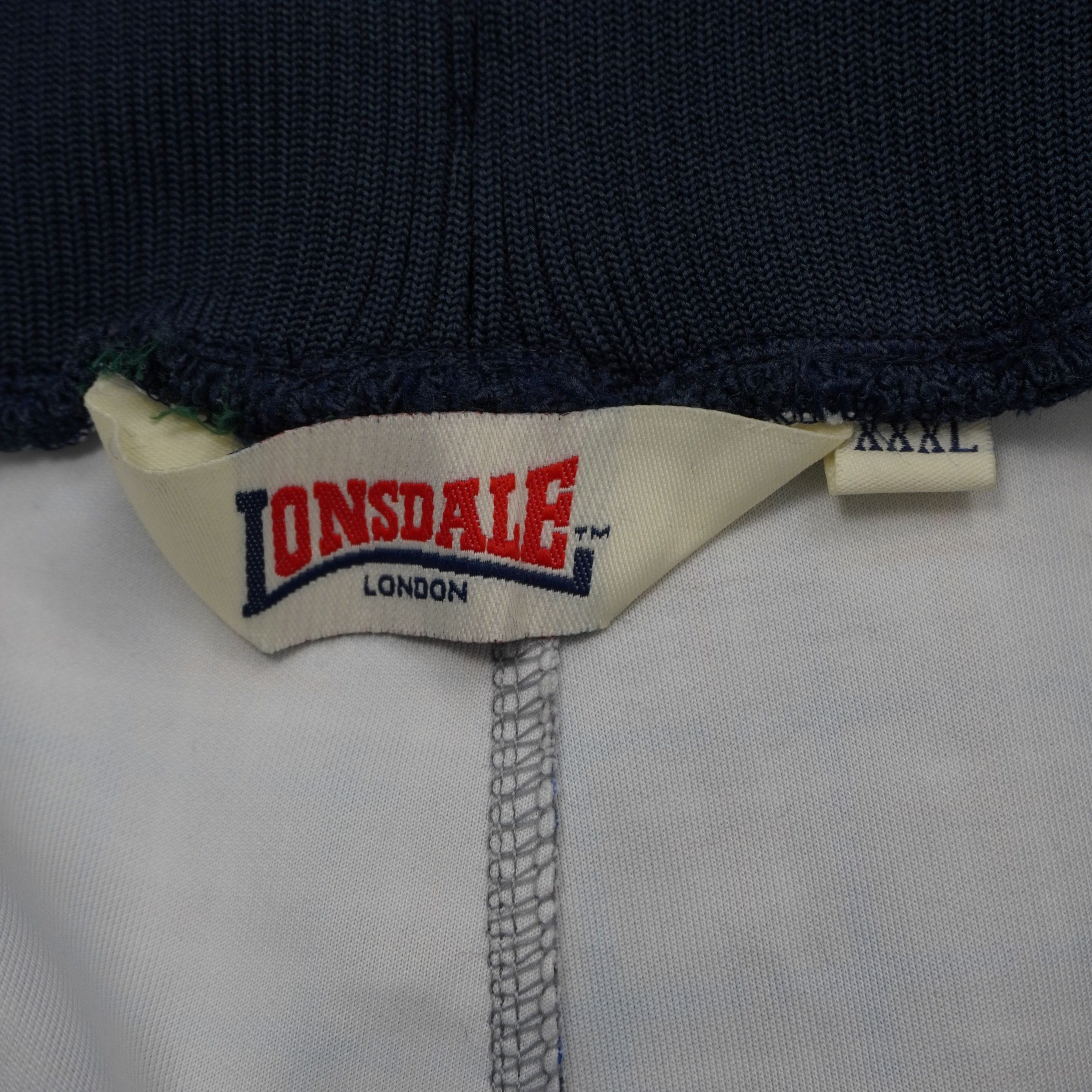 Dettaglio etichetta interna logo Lonsdale London con tag taglia XXXL cucito su pantalone da tuta