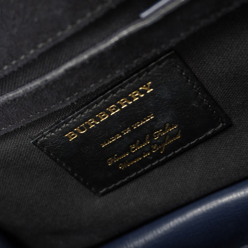 Etichetta interna in pelle nera con logo Burberry stampato in oro e dicitura di autenticità Made in Italy.