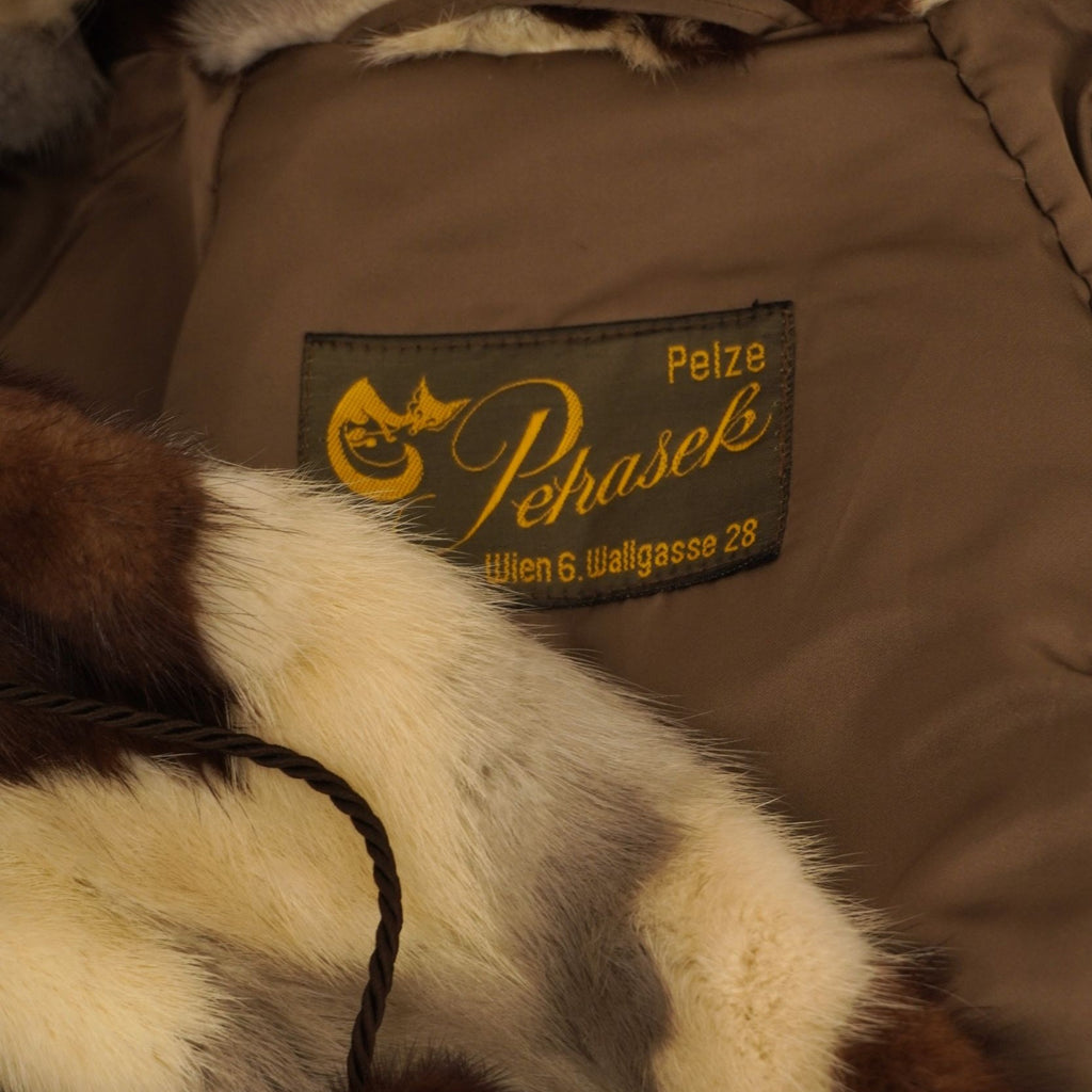 Primo piano dell'etichetta sartoriale dorata vintage Pelze Pehasek Wien cucita sulla fodera interna marrone della pelliccia.