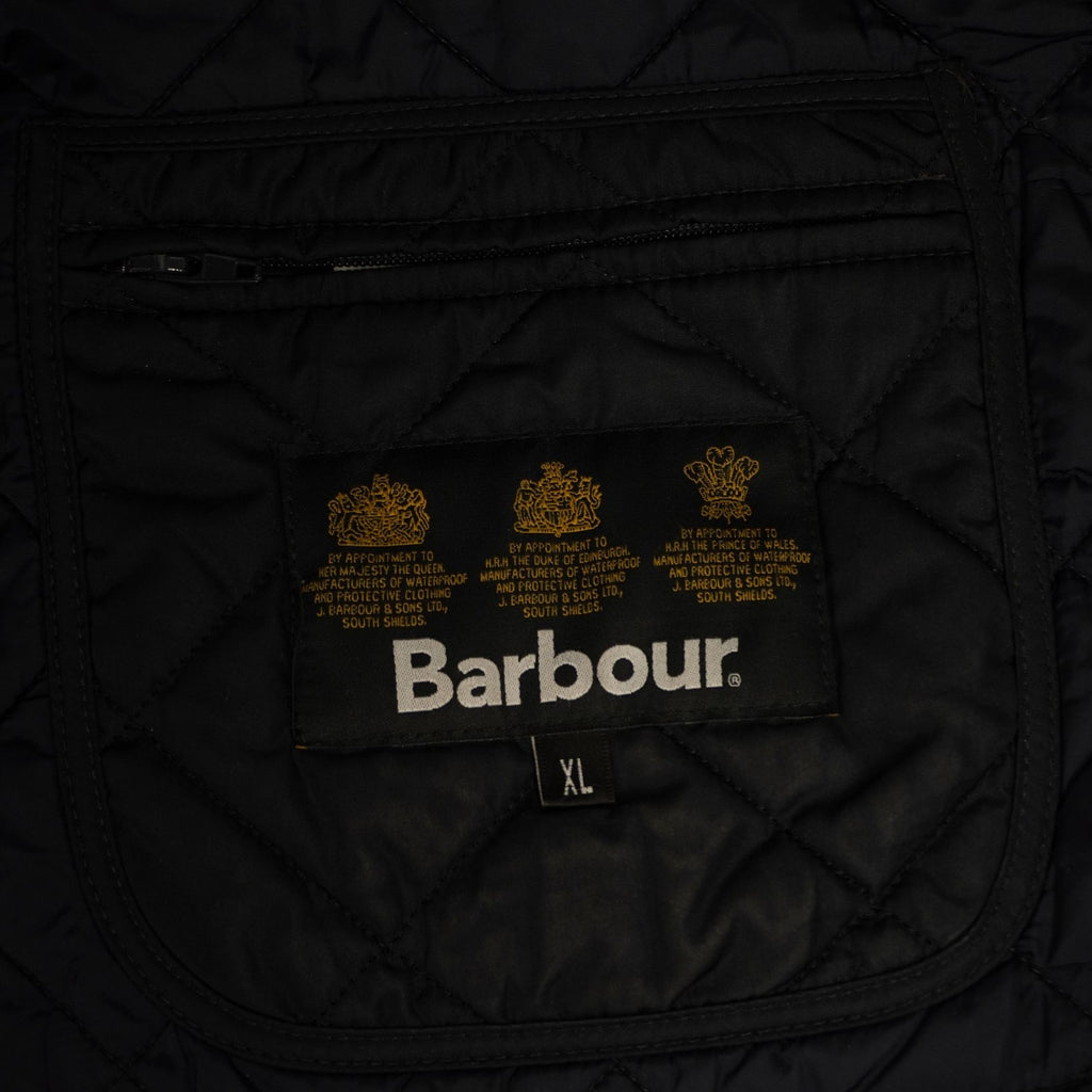 Dettaglio del logo Barbour dorato ricamato con i tre stemmi dei mandati reali ("Royal Warrants") sulla fodera interna nera.
