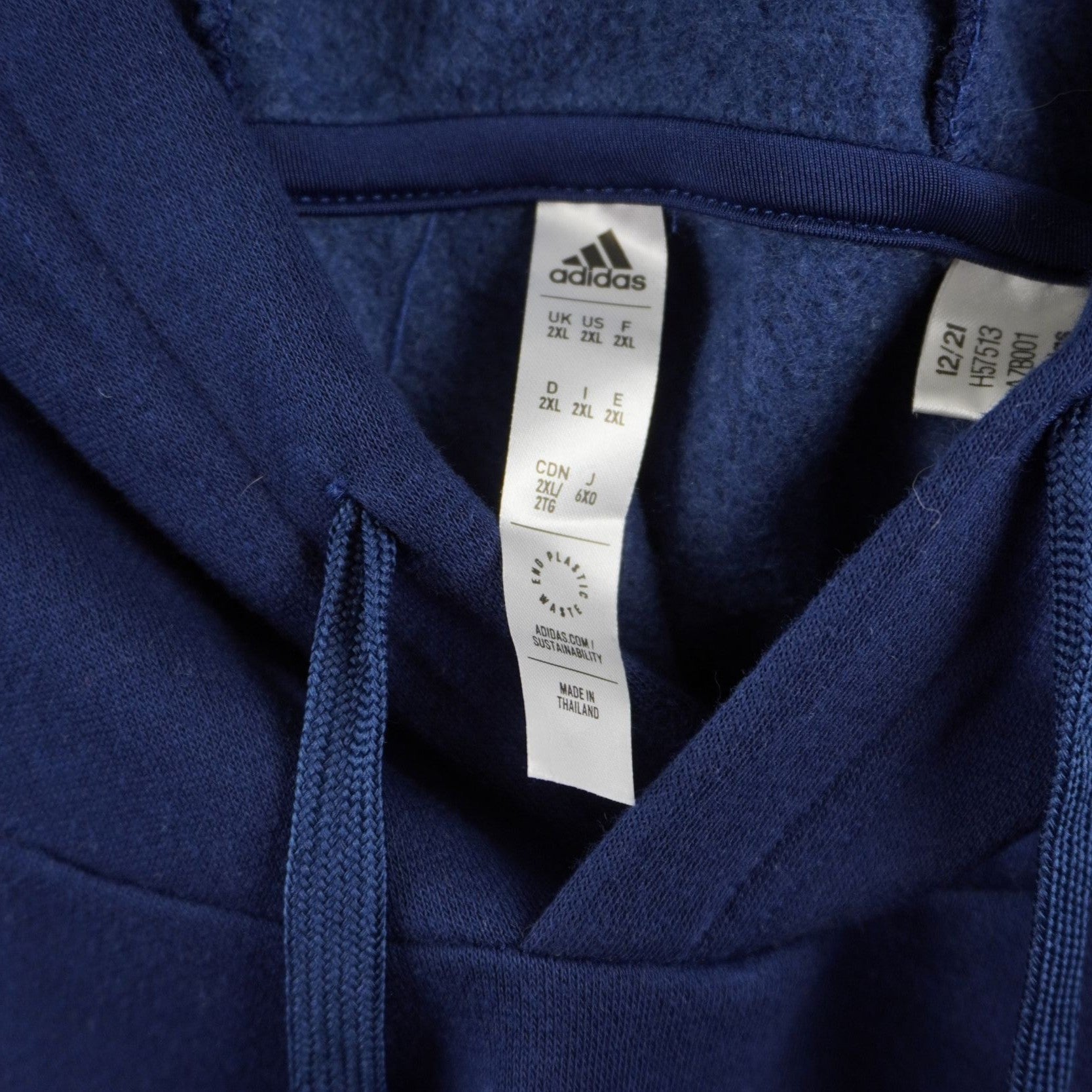 Dettaglio dell'etichetta interna bianca applicata sul collo della felpa adidas, che mostra le specifiche della taglia e l'autenticità del brand.