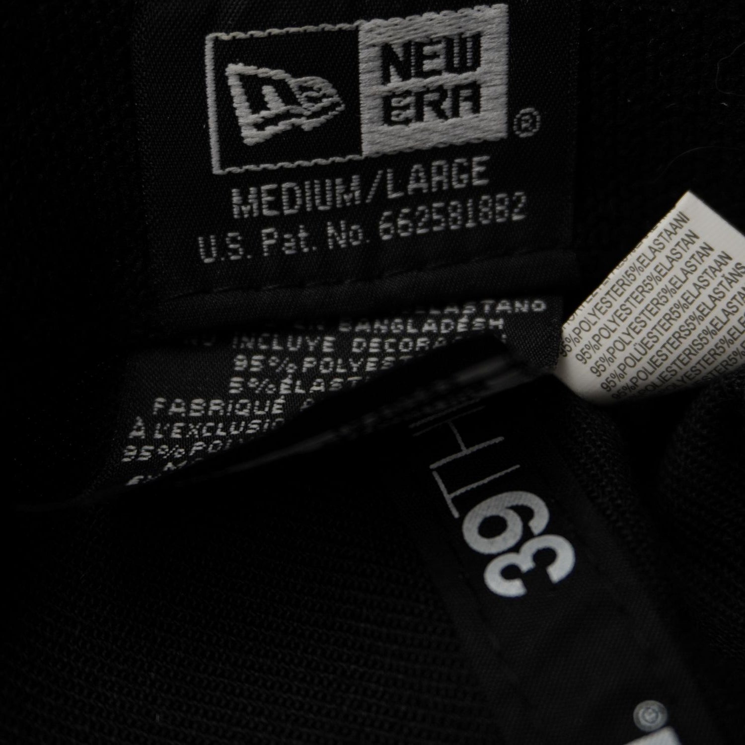 Dettaglio dell'etichetta interna in tessuto nero stampato che mostra il marchio New Era e la taglia Medium/Large (M/L).