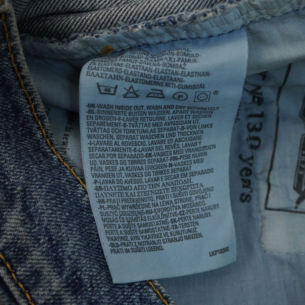 Primo piano del tag interno azzurro verticale con le specifiche per il lavaggio e la cura del denim.