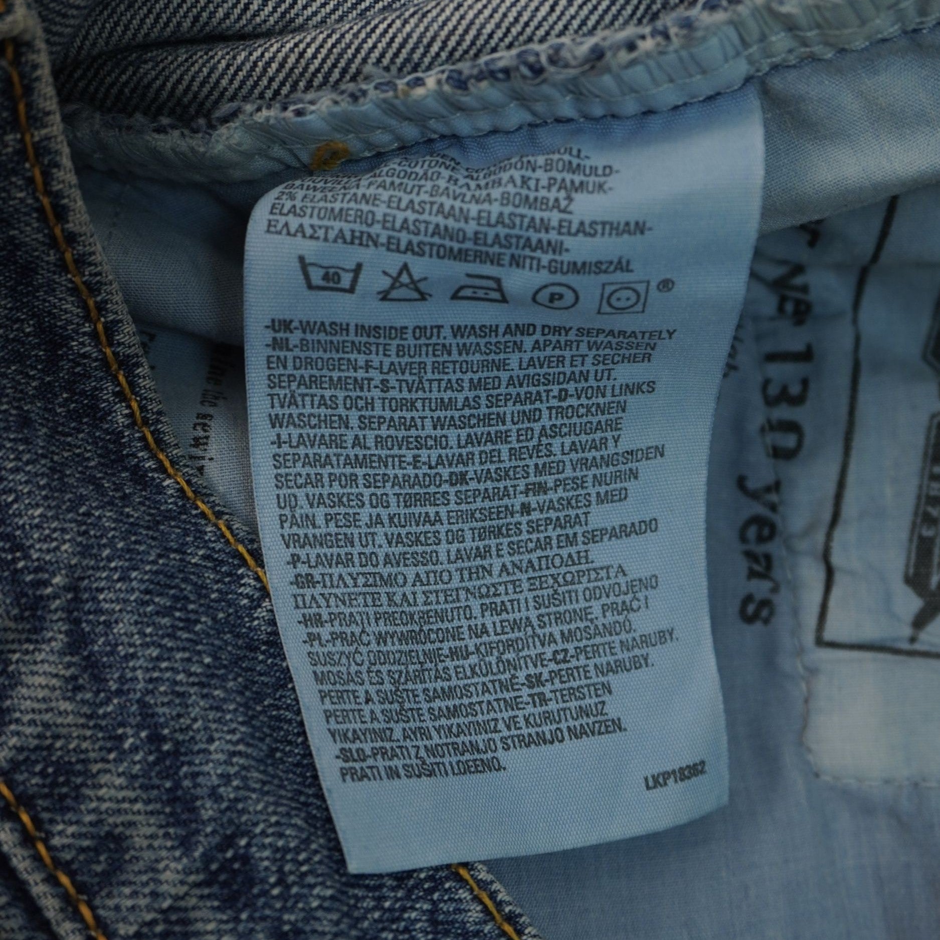 Primo piano del tag interno azzurro verticale con le specifiche per il lavaggio e la cura del denim.