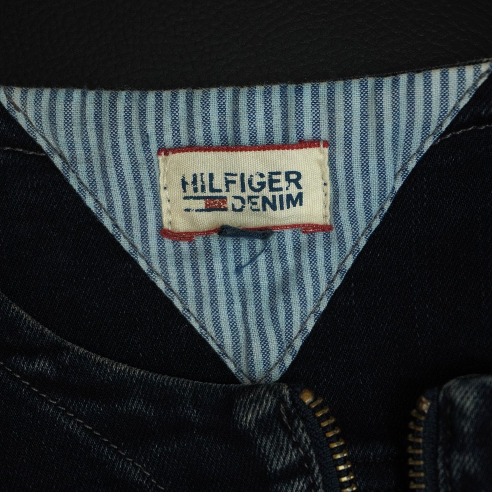 Dettaglio della fodera interna sul collo con l'inserto in tessuto a righe azzurre e bianche e l'etichetta triangolare Hilfiger Denim.
