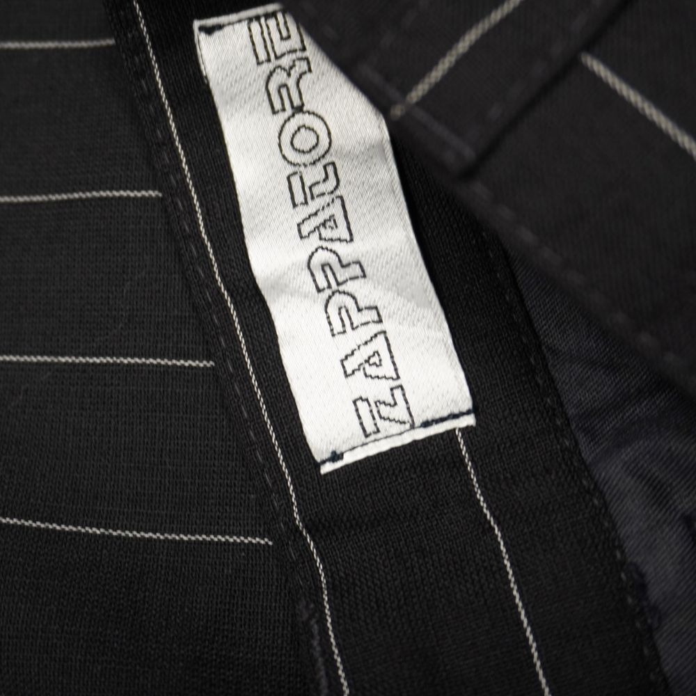 Dettaglio dell'etichetta bianca del brand Zappatore cucita sulla fodera interna della cintura dei pantaloni.