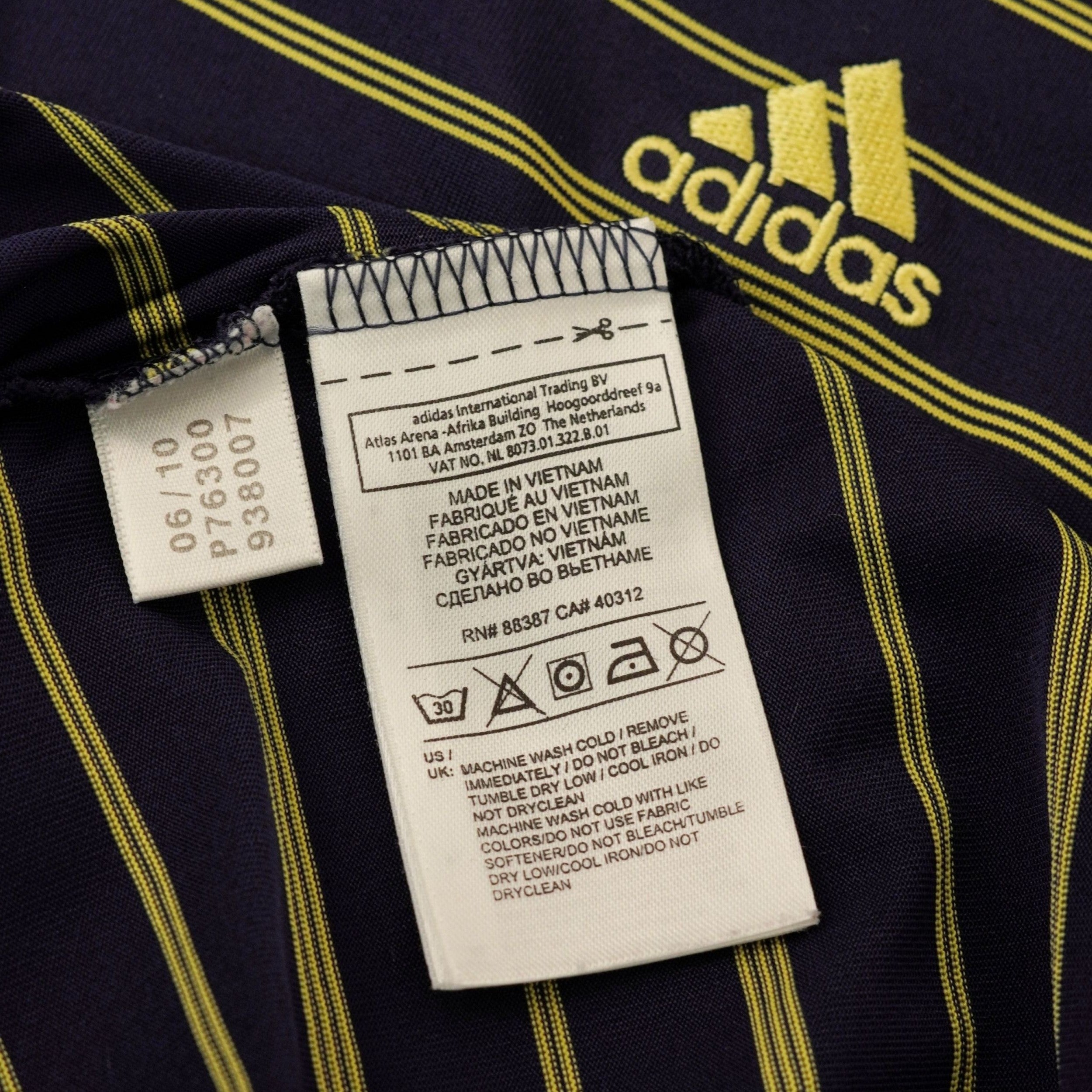  Etichetta interna in tessuto bianco con istruzioni di cura, simboli di lavaggio e codici del prodotto vintage adidas.