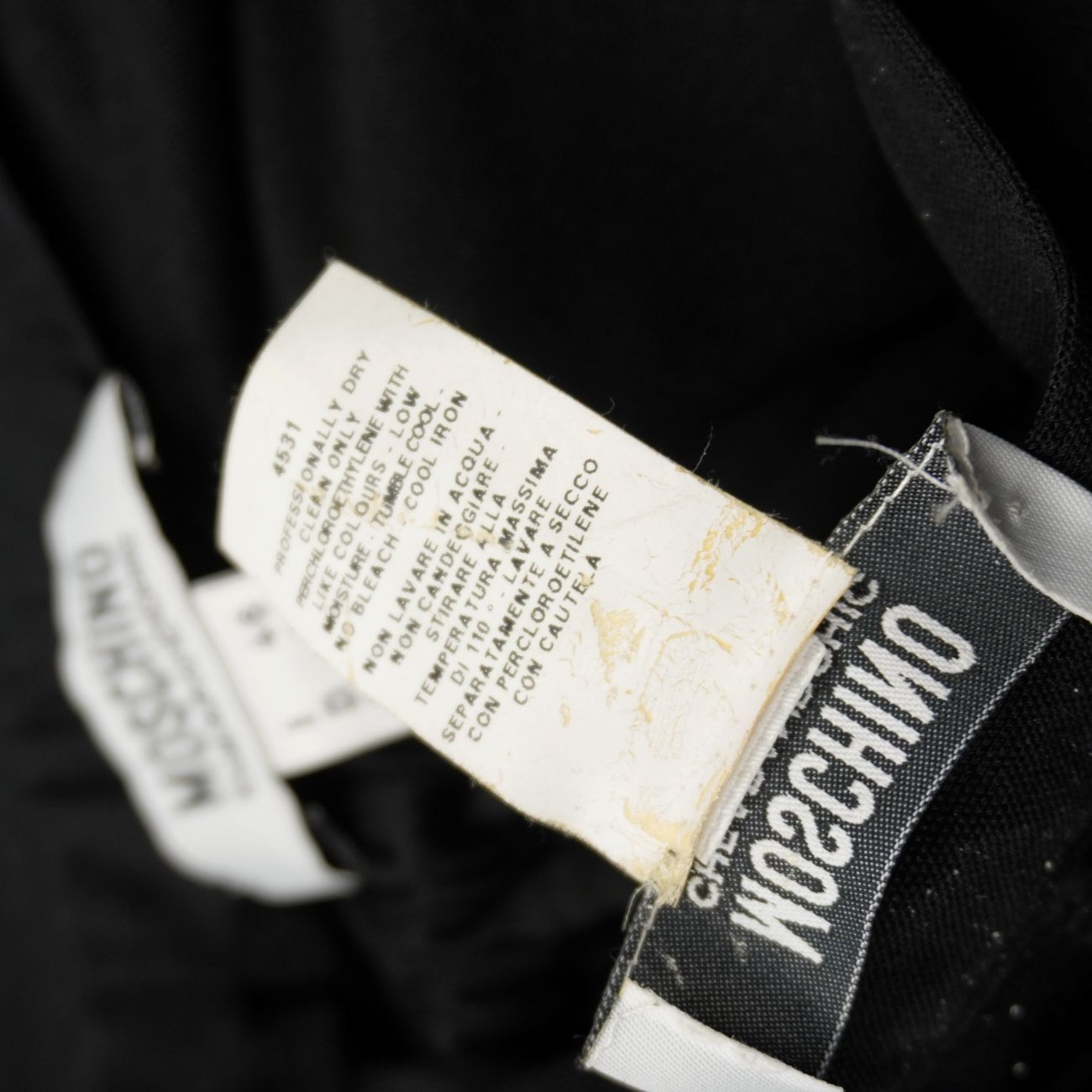 Dettaglio etichetta interna con istruzioni per il lavaggio a secco del completo Moschino.