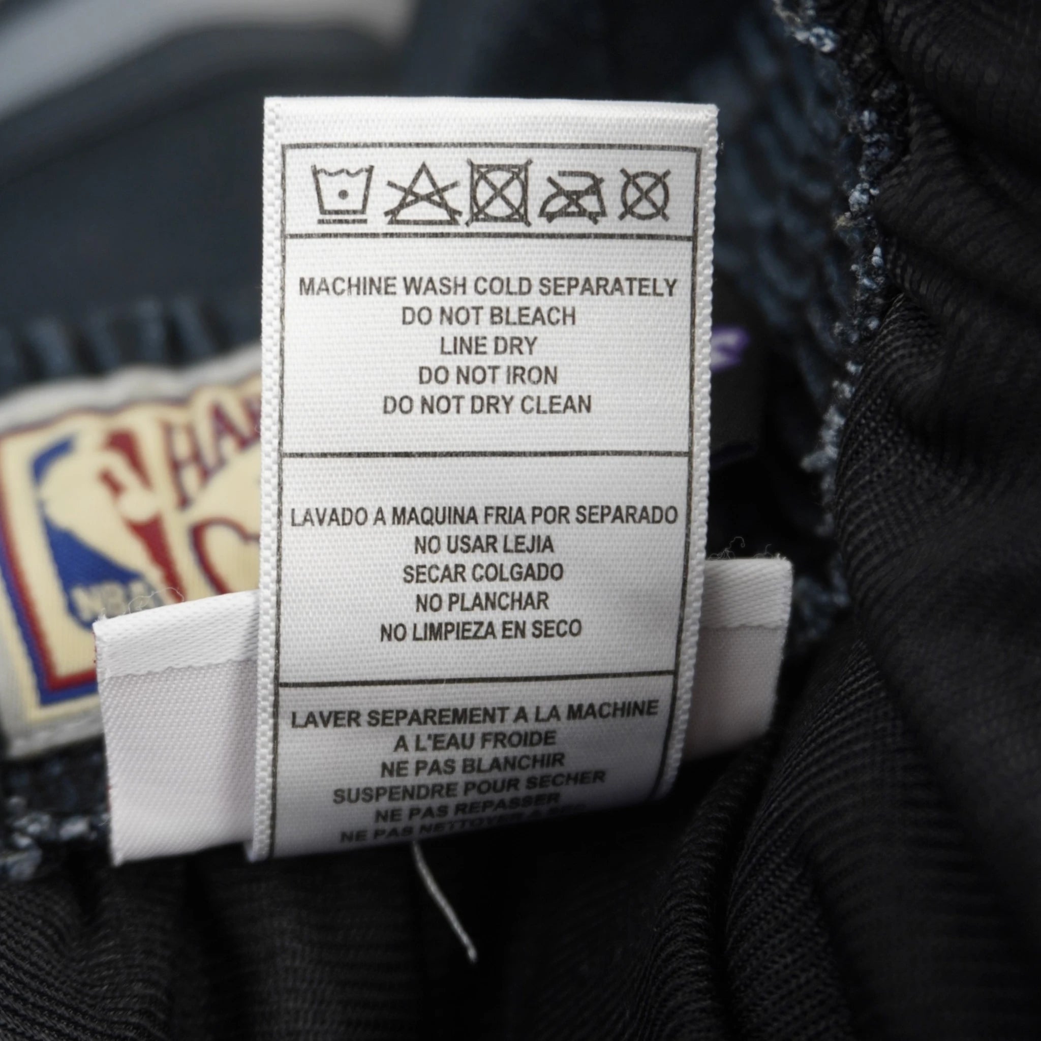 Etichetta interna con istruzioni di lavaggio e cura per shorts Mitchell e Ness Hardwood Classics