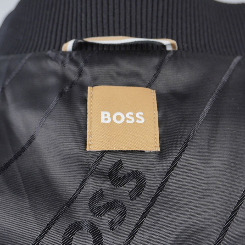 Dettaglio dell'etichetta quadrata color oro con il logo BOSS cucita sulla fodera interna nera della giacca, sotto il passante per appendere il capo.