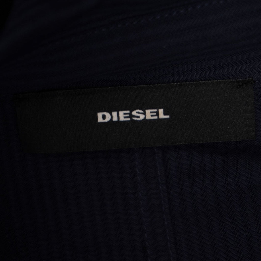 Inquadratura ravvicinata del logo Diesel scritto in bianco su una piccola etichetta rettangolare nera applicata sul capo.
