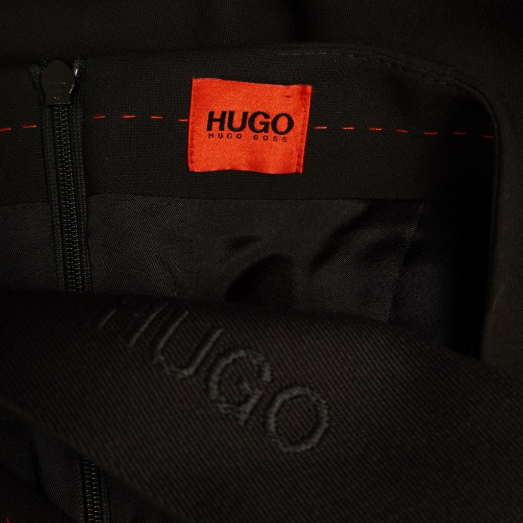 Dettaglio dell'iconica etichetta interna rettangolare rossa con brand HUGO su tessuto nero.