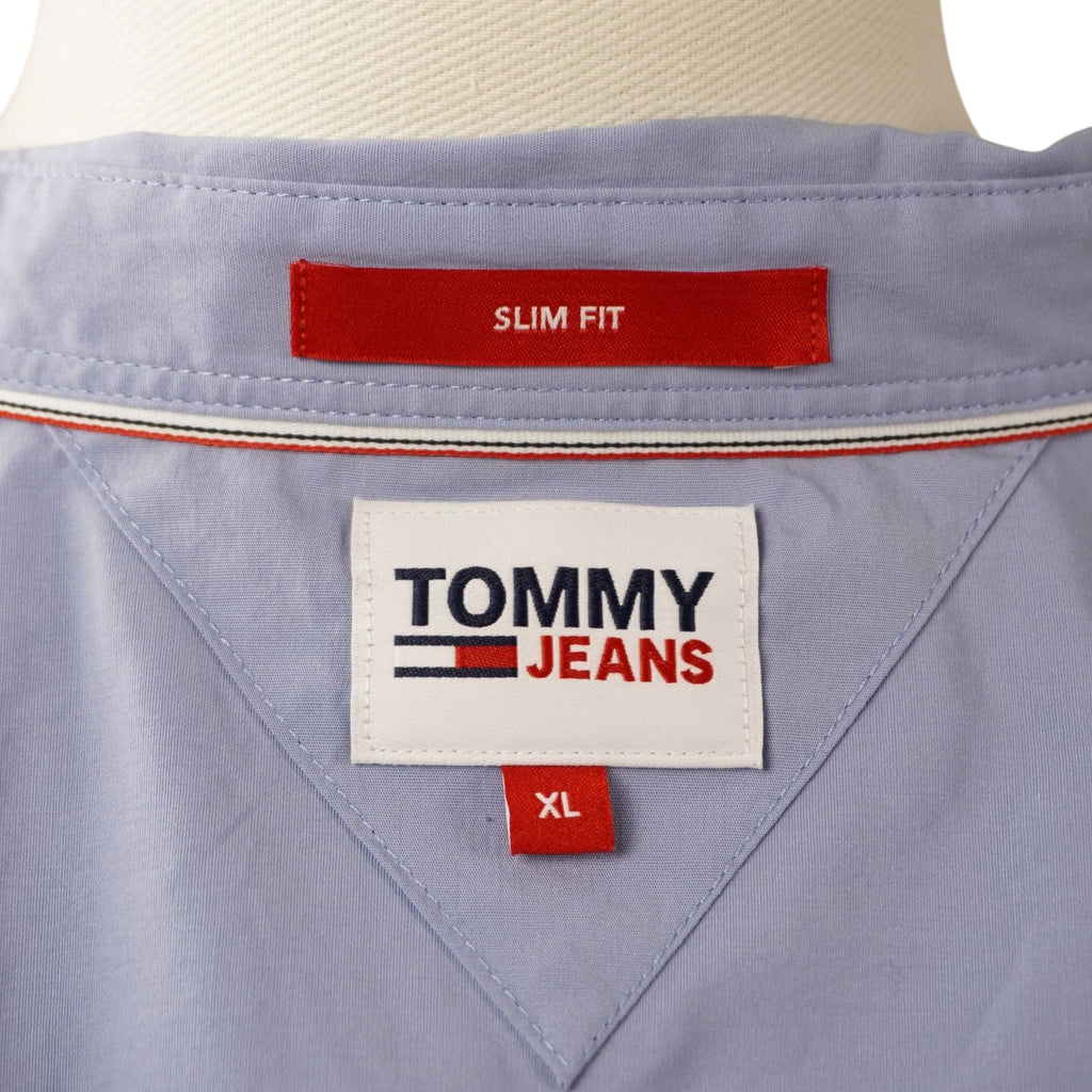  Dettaglio dell'etichetta interna quadrata bianca Tommy Jeans con indicazione della taglia XL e profilo rosso Slim Fit.