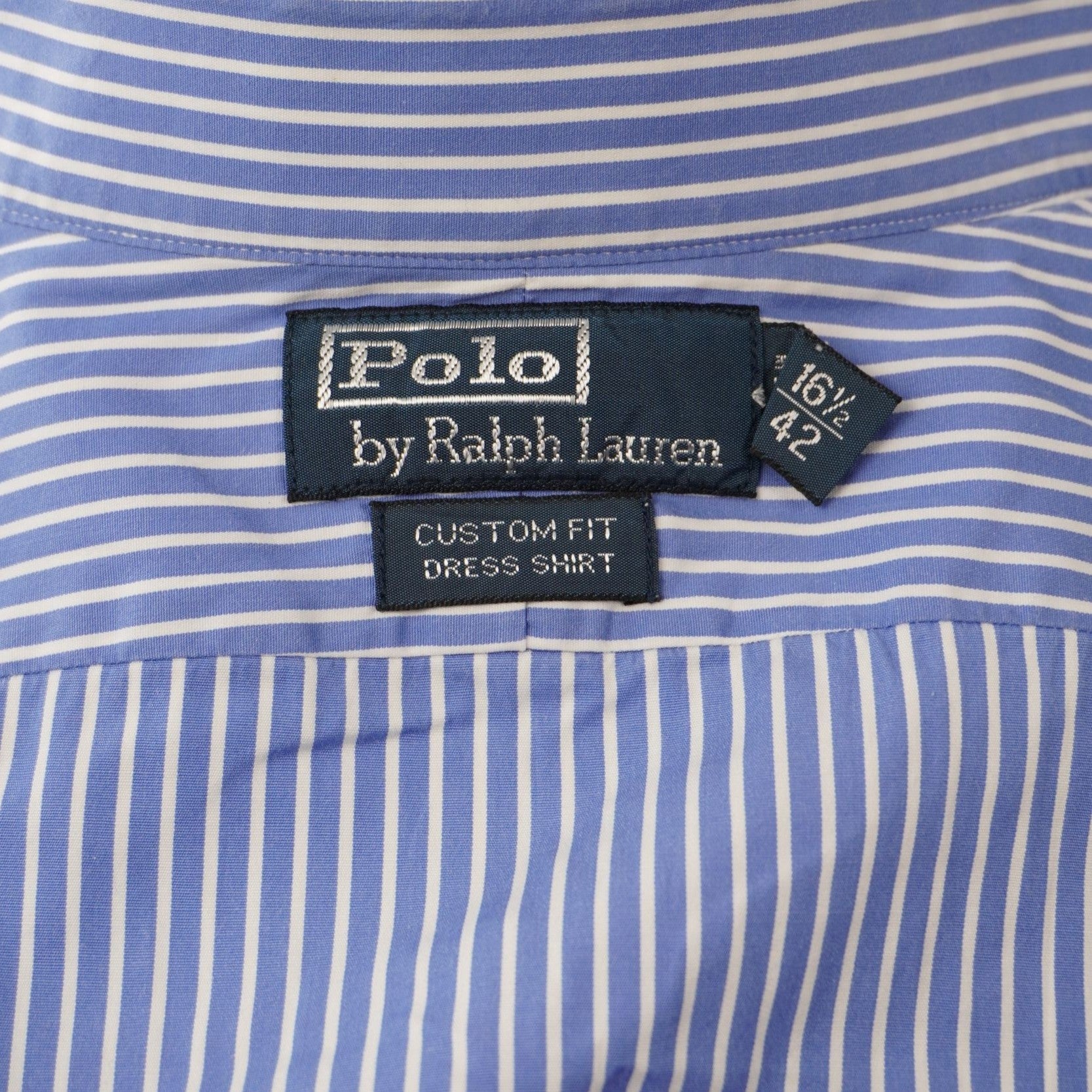 Dettaglio dell'etichetta interna blu scuro Polo by Ralph Lauren cucita sul colletto con l'indicazione della taglia XL.