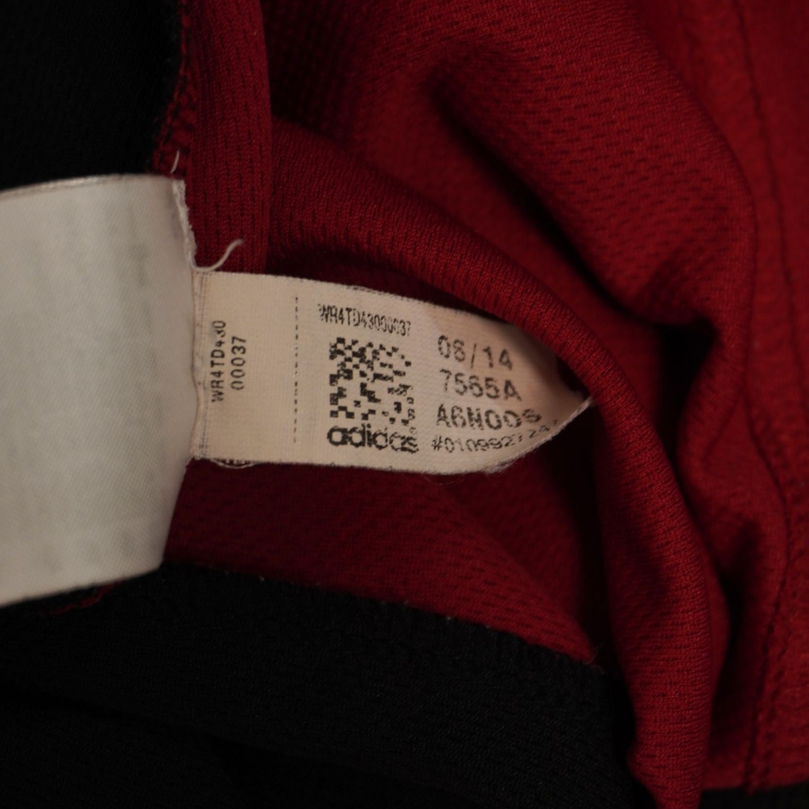 Primo piano della piccola etichetta interna bianca che indica la produzione Made in Vietnam e i codici di tracciabilità del capo.