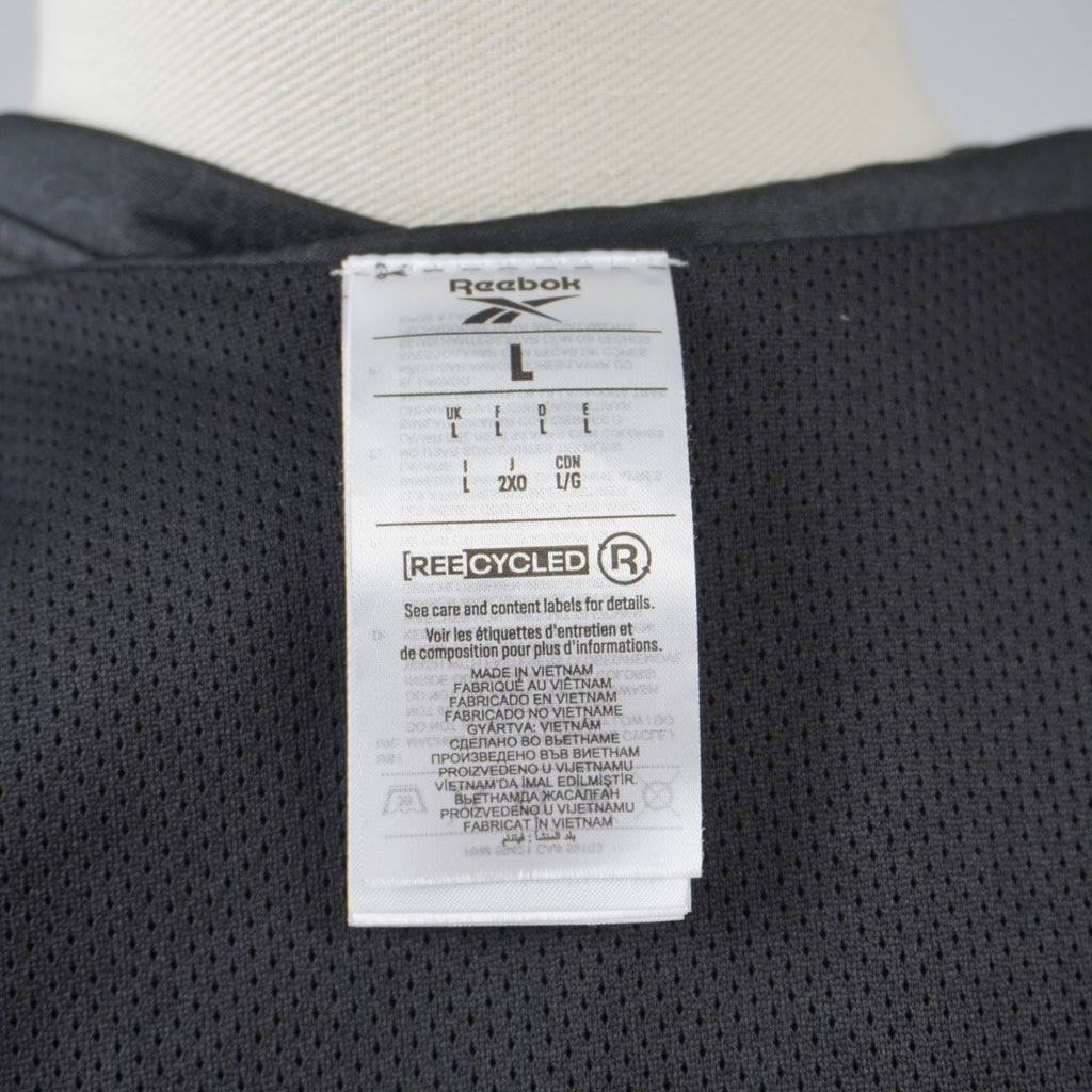 Inquadratura ravvicinata del logo Reebok e dell'indicazione della linea ecosostenibile stampati internamente sotto il colletto.