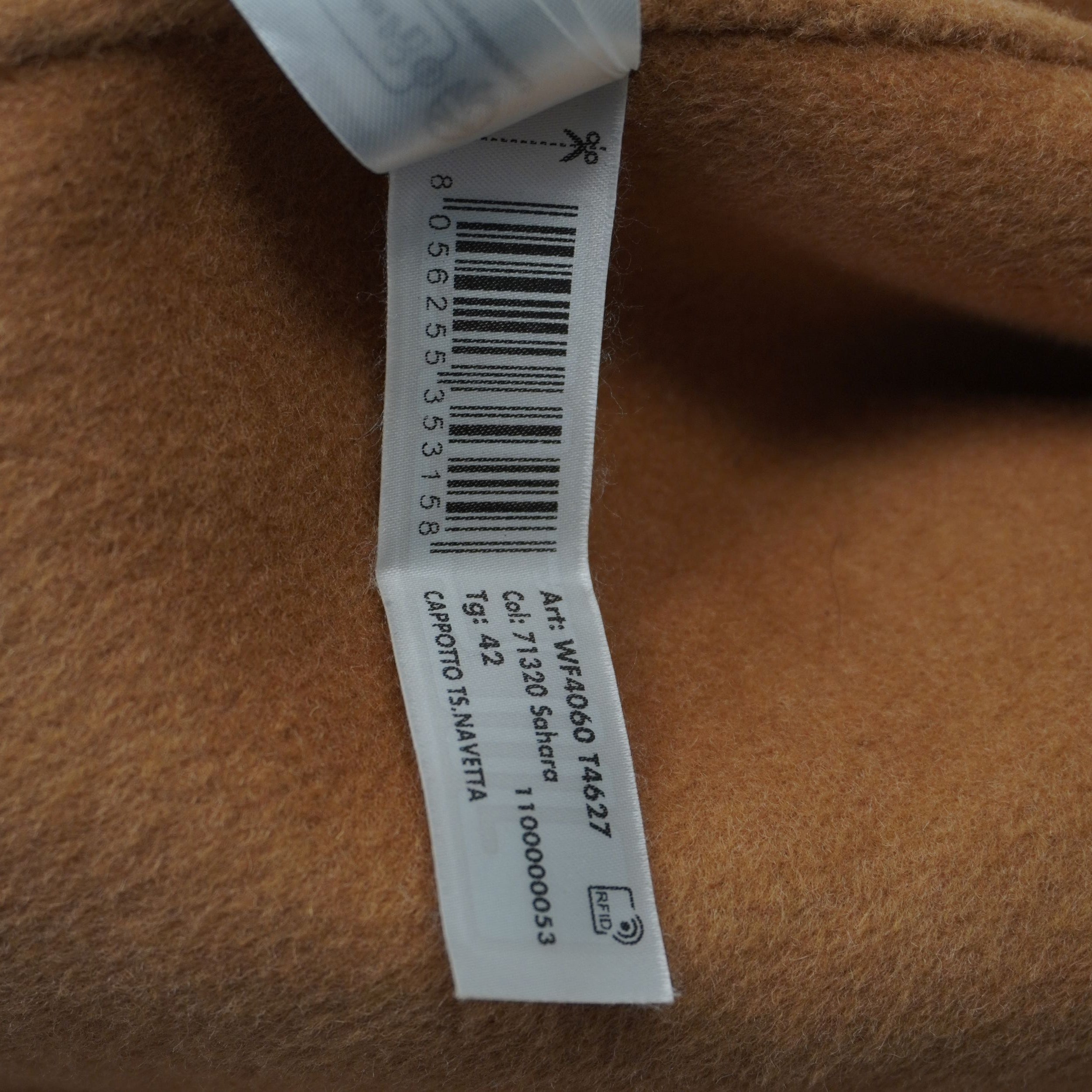 Dettaglio dell'etichetta interna con tecnologia RFID e codici prodotto per certificare l'originalità del cappotto.