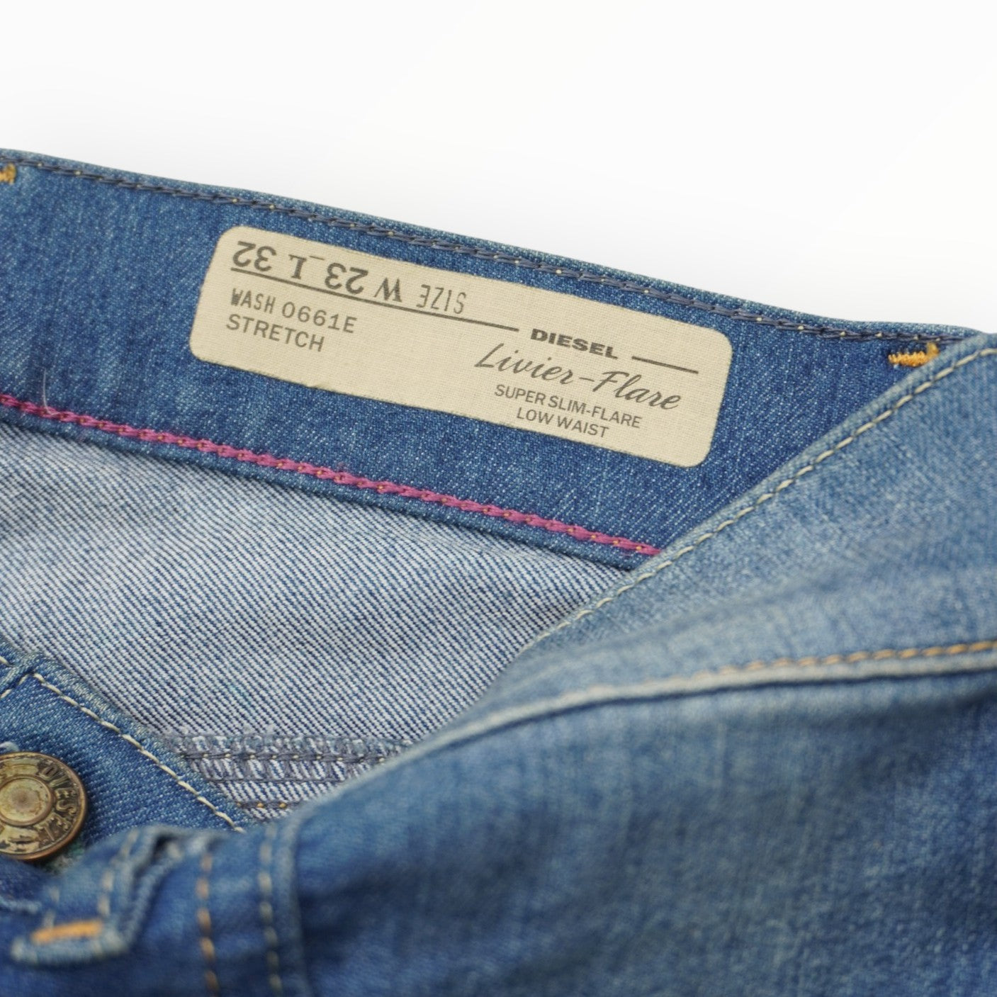 Particolare dell'etichetta in tessuto beige con scritte ricamate applicata all'interno del fascione della vita dei jeans Diesel.