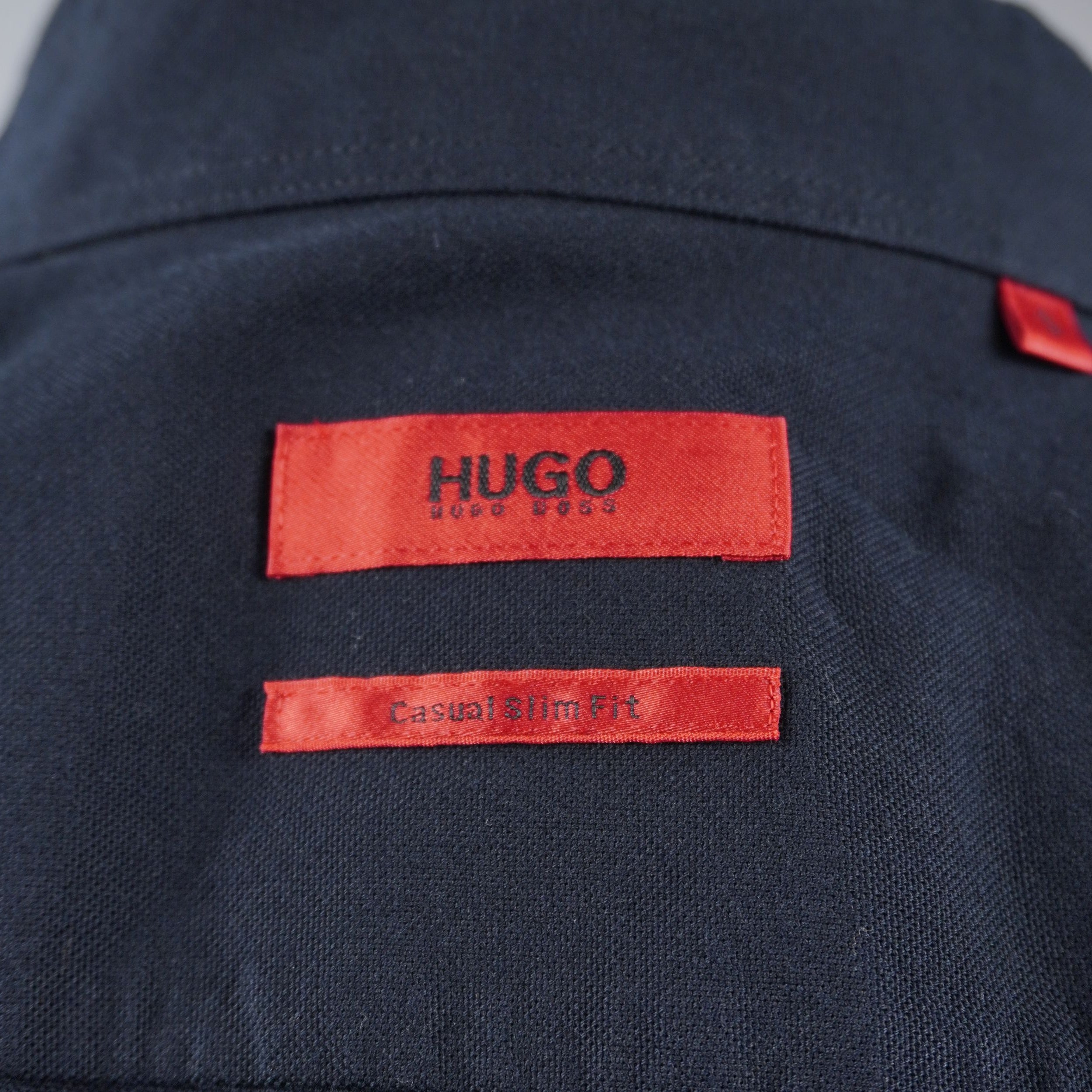 Primo piano dell'etichetta rossa rettangolare HUGO BOSS cucita all'interno del colletto della camicia.