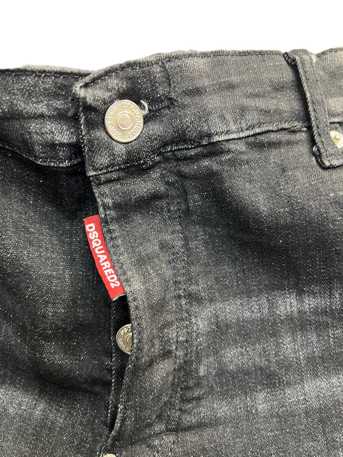 Primo piano della chiusura frontale dei jeans con l'iconica etichetta rossa verticale Dsquared2 sulla patta.