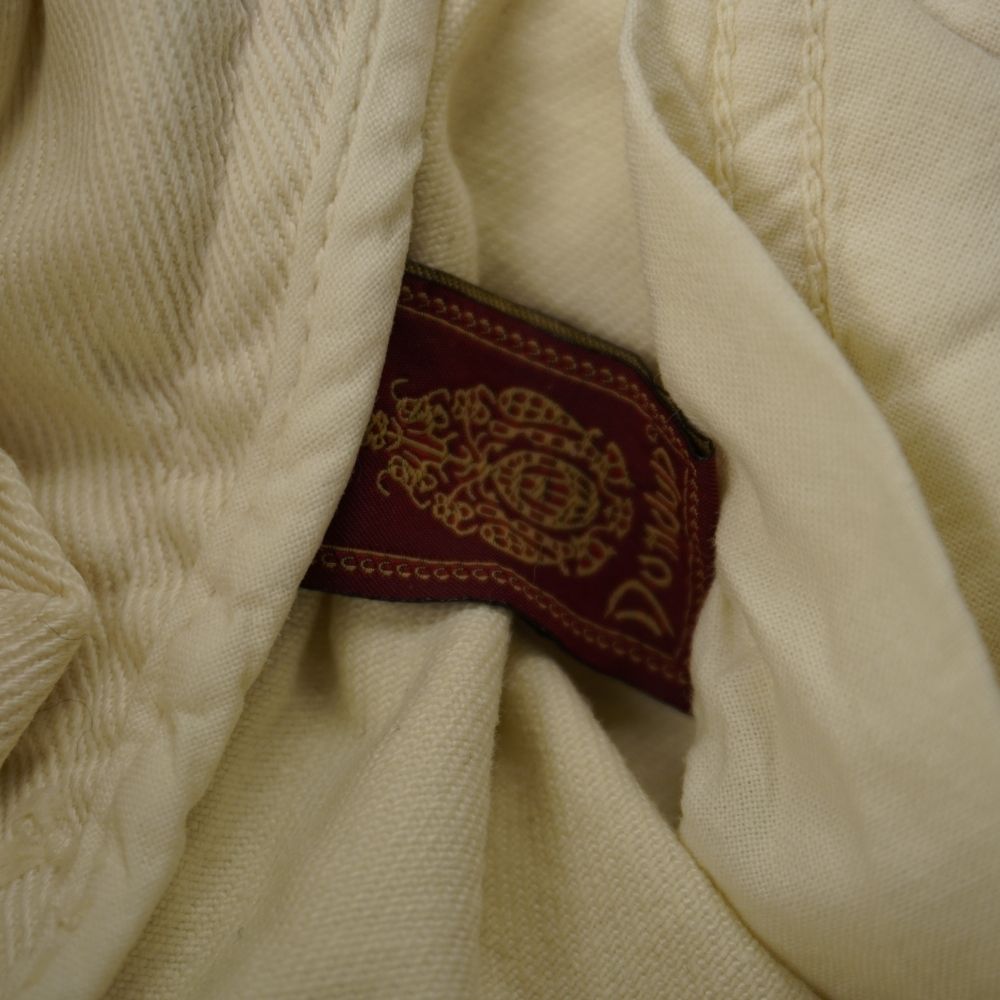 Dettaglio etichetta jacquard bordeaux ricamata con stemma araldico Dondup all'interno della tasca