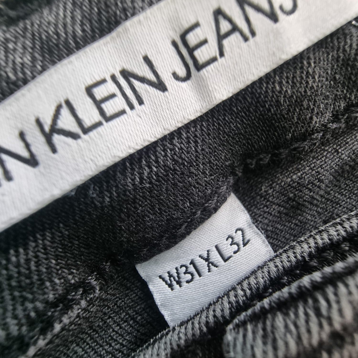 Etichetta interna della taglia americana W31 L32 corrispondente alla taglia 45 italiana su jeans neri Calvin Klein
