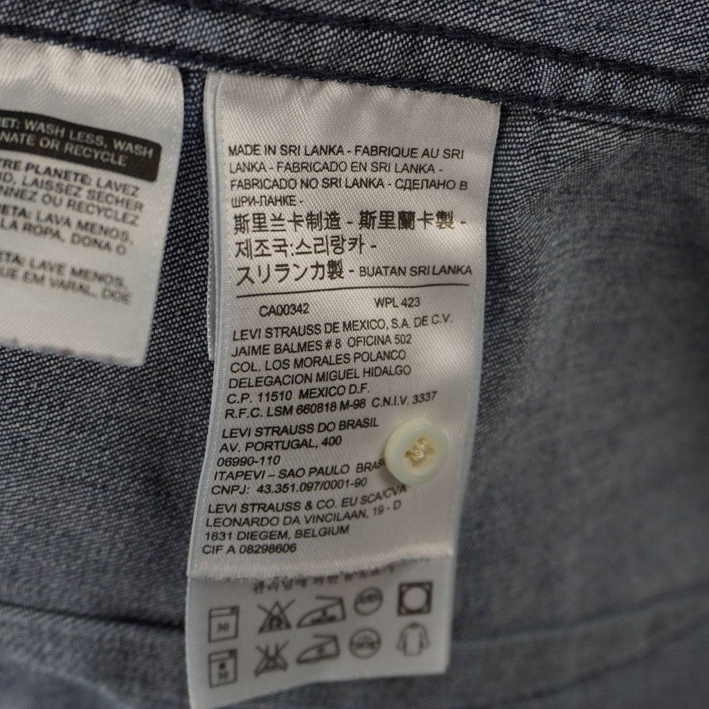 Dettaglio dell'etichetta tecnica che indica la taglia XS e la composizione del tessuto in denim di cotone.