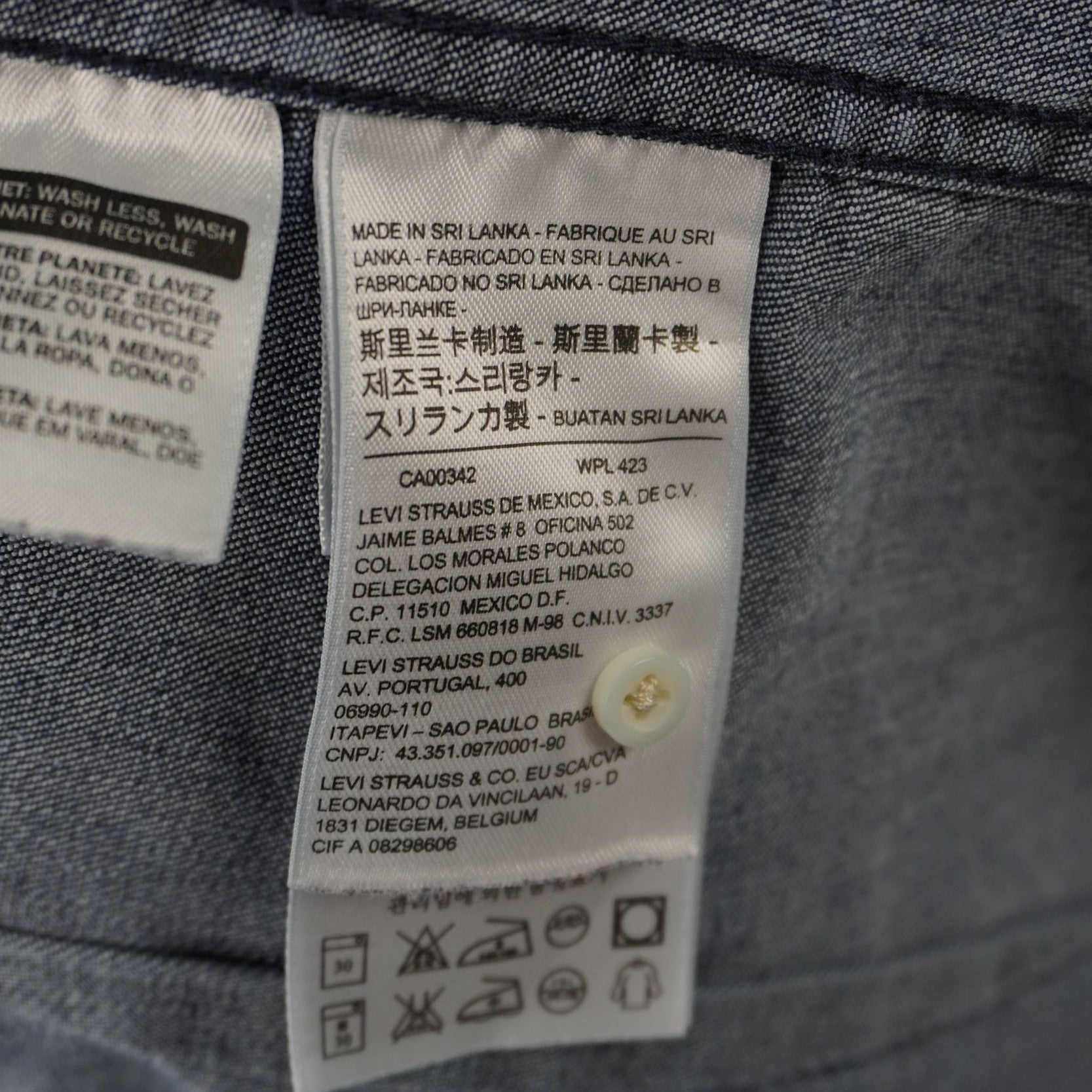 Dettaglio dell'etichetta tecnica che indica la taglia XS e la composizione del tessuto in denim di cotone.