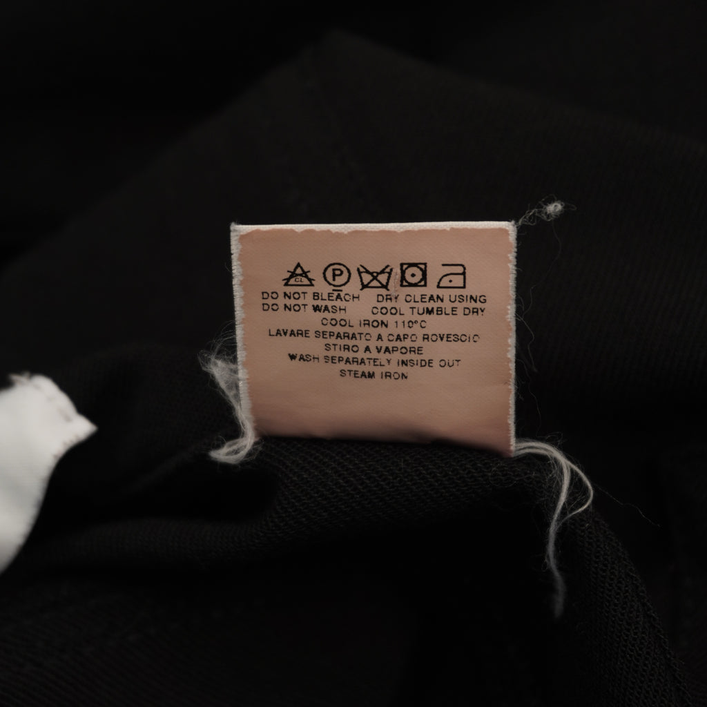 Macro del tag tecnico interno bianco che riporta i codici identificativi di serie della linea Moschino Jeans.