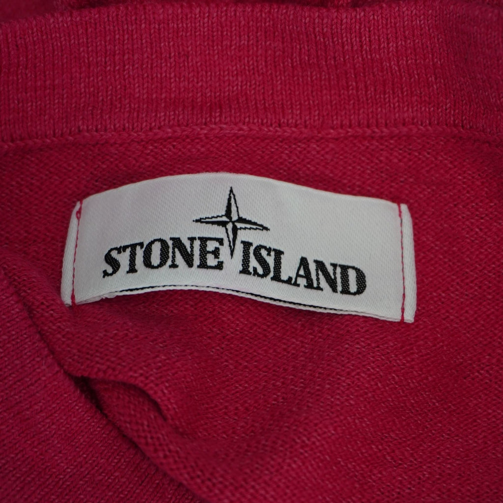 Dettaglio dell'etichetta rettangolare bianca in tessuto con il logo della rosa dei venti e la scritta Stone Island cucita all'interno della scollatura.