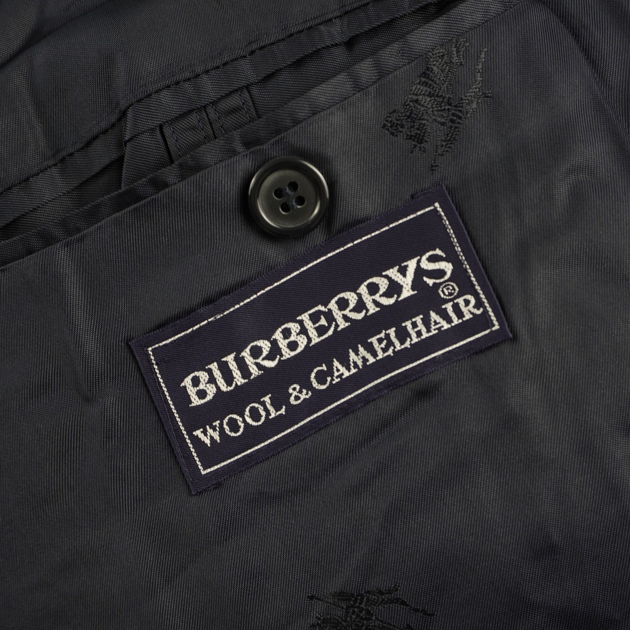 Dettaglio della seconda etichetta in tessuto nero con ricamata la scritta "Burberrys' WOOL & CAMELHAIR" che ne attesta la composizione pregiata.