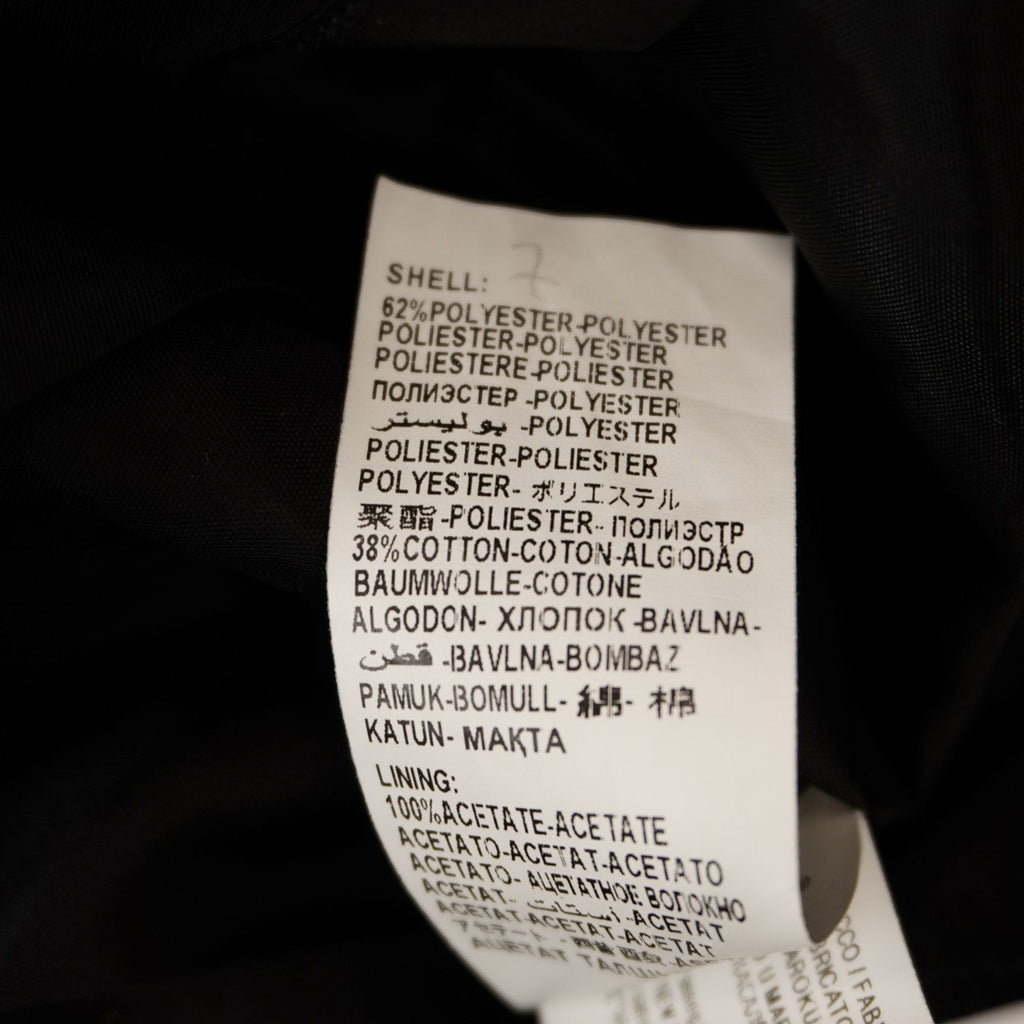 Primo piano dell'etichetta interna che riporta le avvertenze per la cura del capo e i dati del brand.
