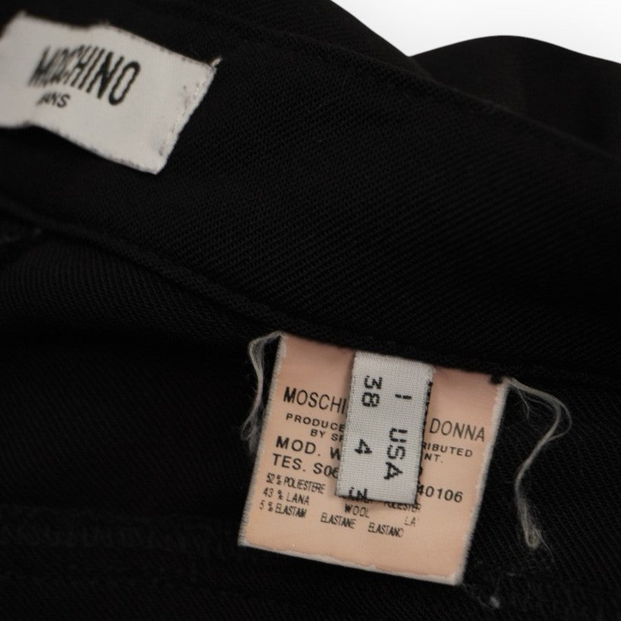 Inquadratura ravvicinata del cartellino interno in tessuto dal sapore vintage cucito lungo la fodera del pantalone.