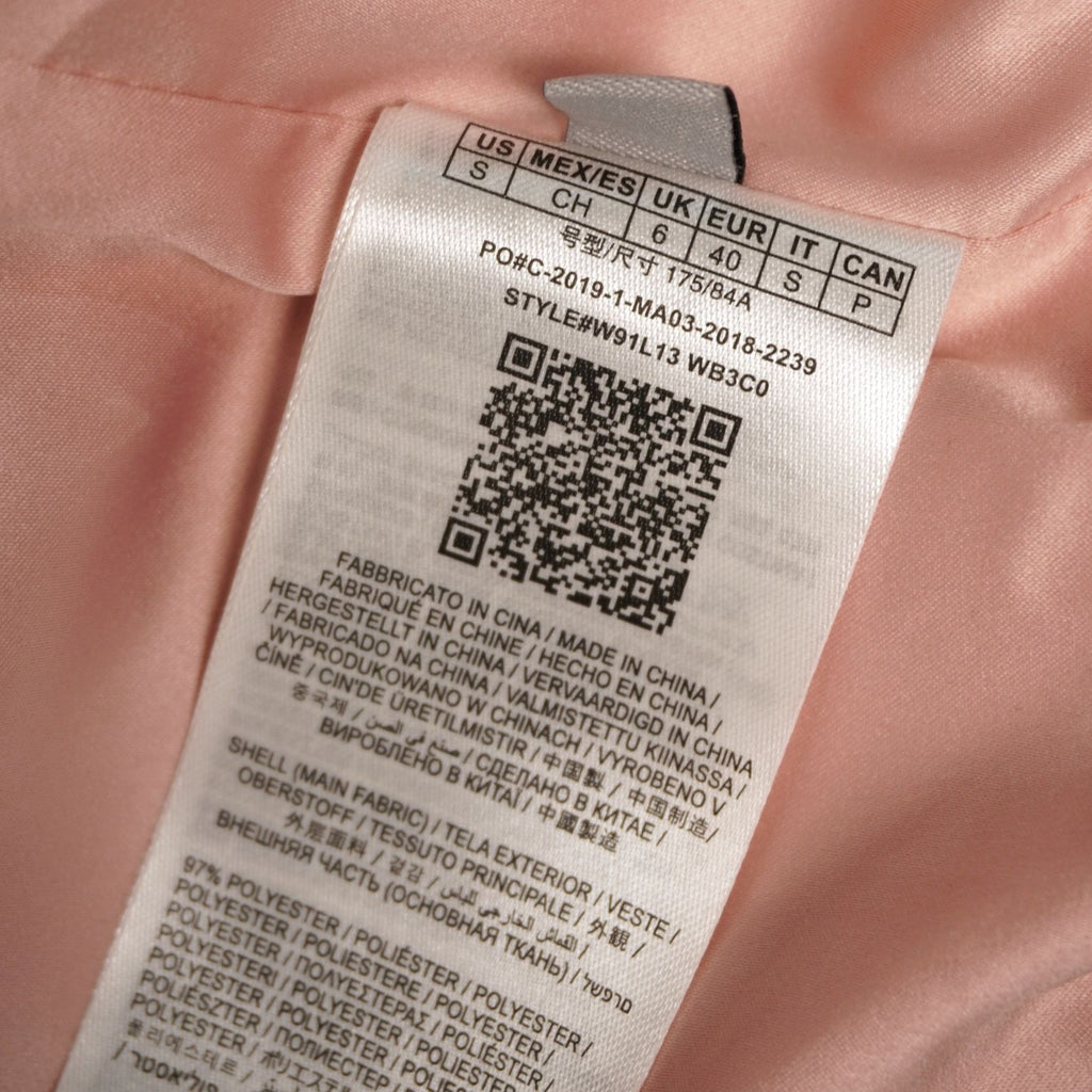 Inquadratura ravvicinata dell'etichetta interna bianca con codice QR, codice stile W91L13 e specifiche del brand Guess.