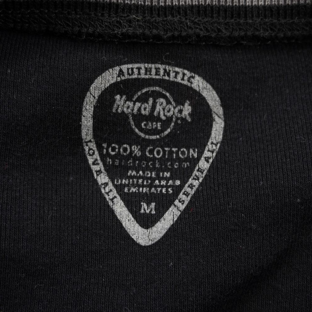 Dettaglio dell'etichetta interna d'archivio stampata a forma di plettro con taglia M e logo Hard Rock Cafe.