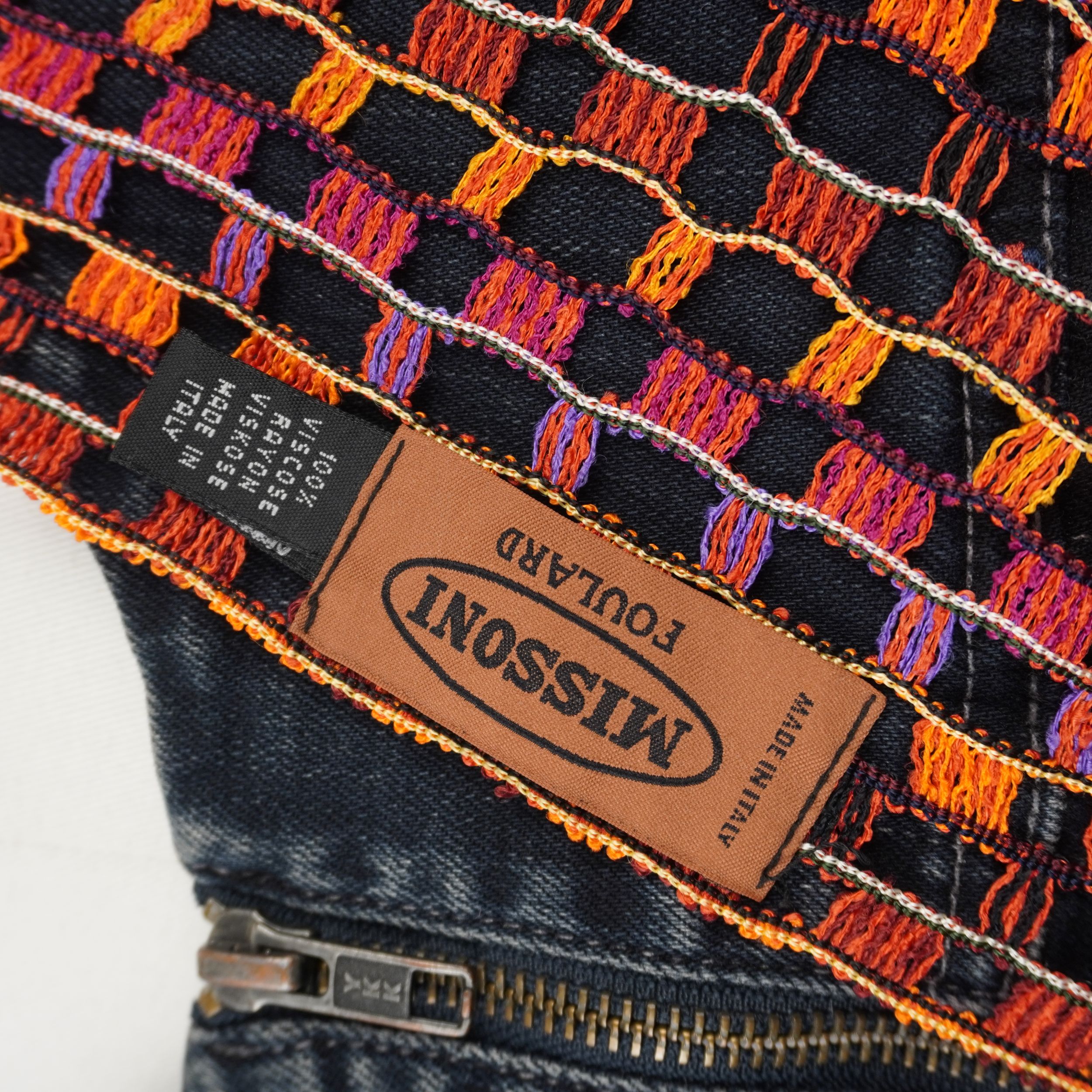 Primo piano dello storico logo ricamato rettangolare marrone Missoni cucito sulla trama a rete della sciarpa vintage originale.