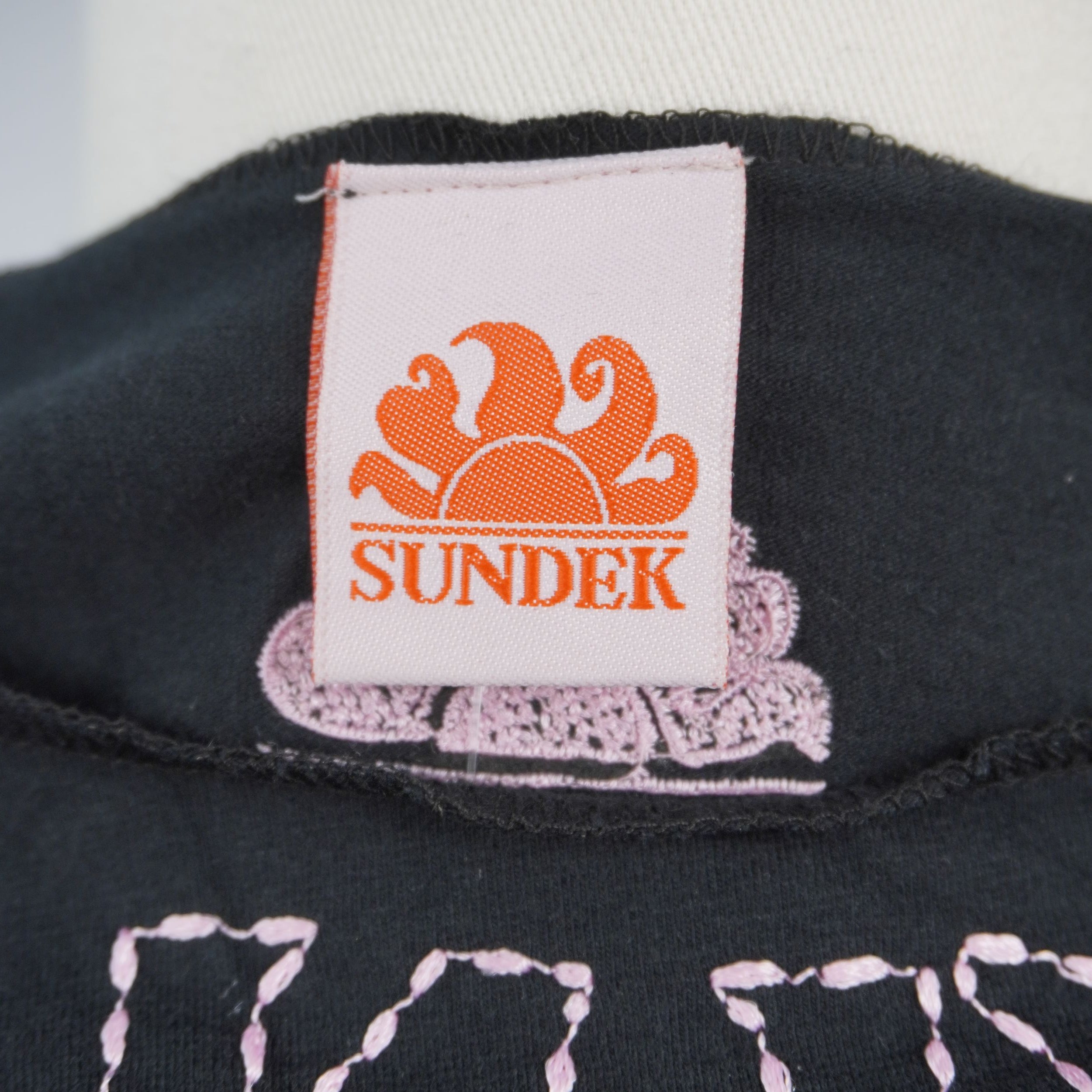 Etichetta originale Sundek con l'iconico logo del sole, cucita internamente sul colletto del capo vintage.