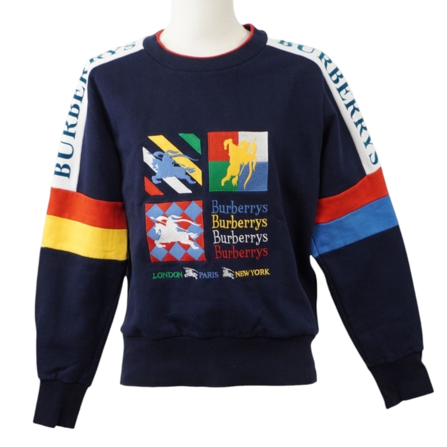 Vista frontale su manichino di una felpa girocollo blu notte Burberry con grafica d'archivio multicolore ricamata sul petto e bande logate sulle spalle.