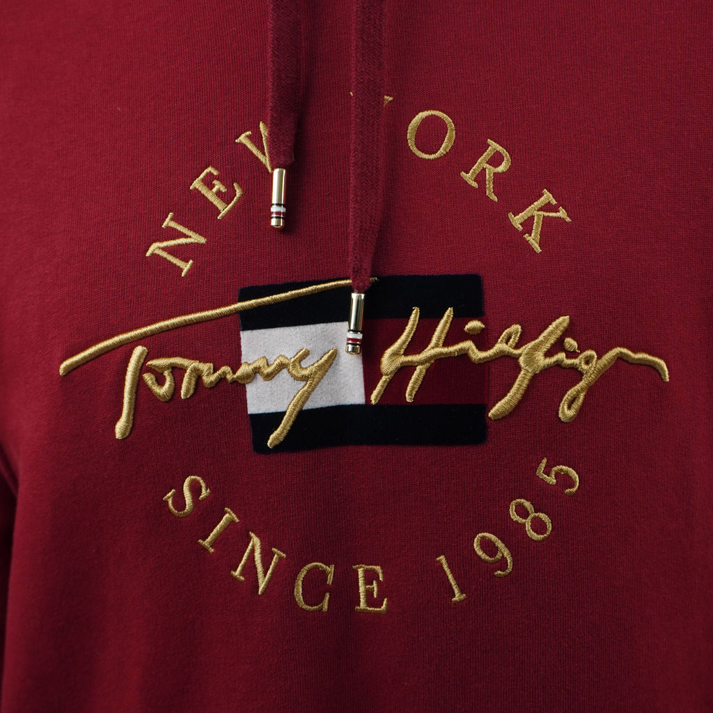 Primo piano del ricamo dorato frontale "Tommy Hilfiger New York Since 1985" sul petto.