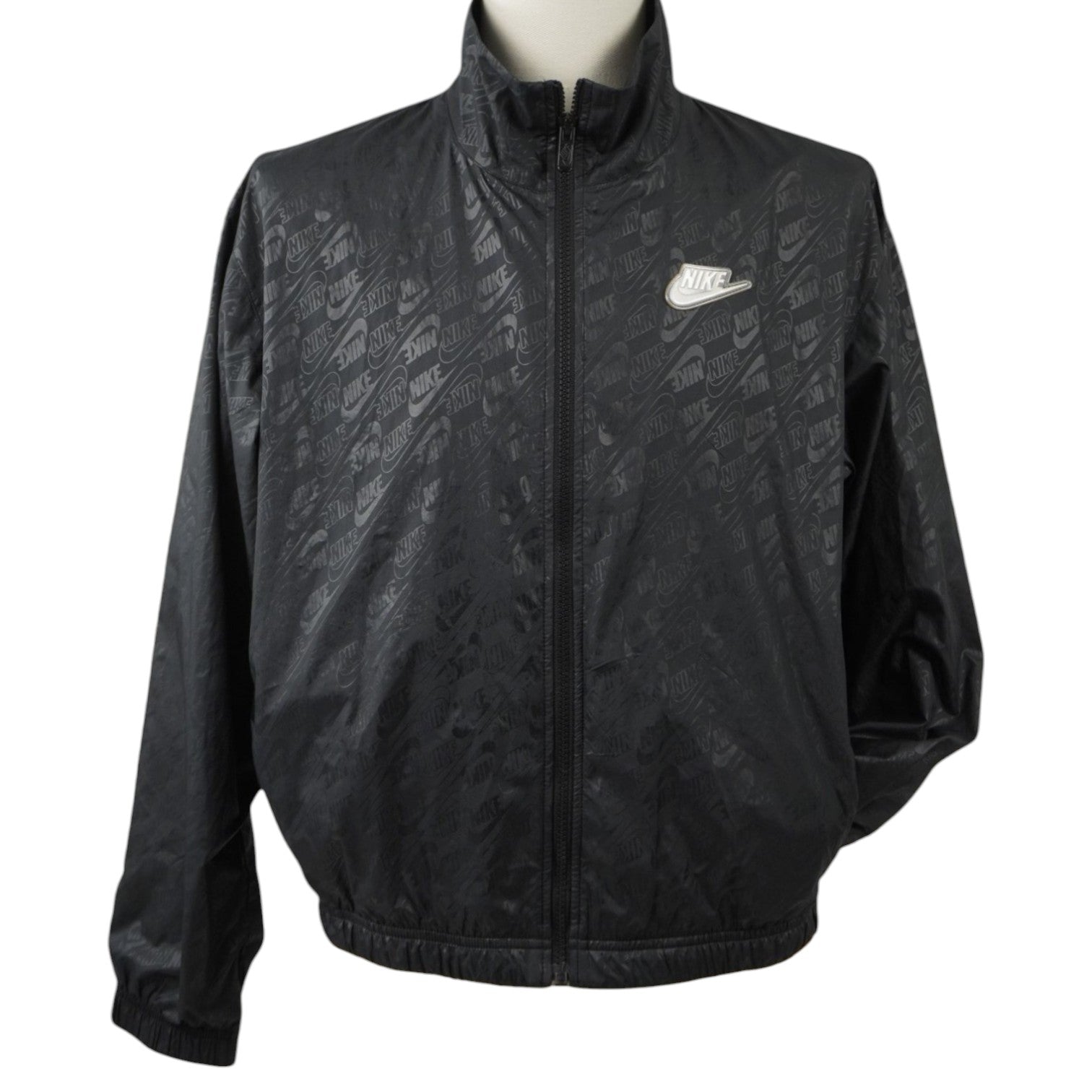 Inquadratura laterale della giacca nera Nike che mette in risalto il taglio relaxed fit e il tessuto lucido opaco.